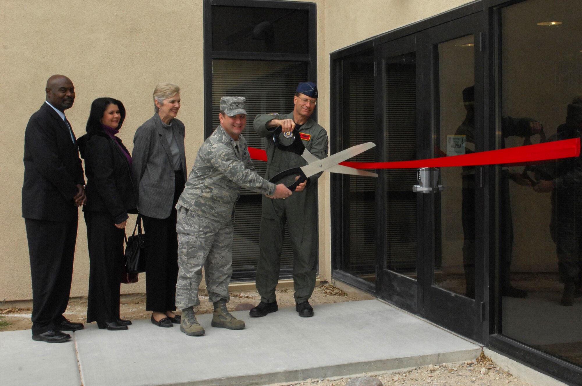 (Right to left) Col. Herman Brunke, 926th Group commander, and Col. Steven Winklmann, 99th Air Base Wing vice commander, cut the ribbon signifying the official opening of the 926th GP’s headquarters building, while observed by Ms. Margot Allen of Senator Ensign’s office, Ms. Roxane Unverrich of Congresswoman Berkley’s office and Mr. Robert Sharp of Senator Reid’s office. The new facility, along with an adjacent building, houses all of the group’s Nellis personnel in one location. (U.S. Air Force photo/Staff Sgt. Erin Worley)
