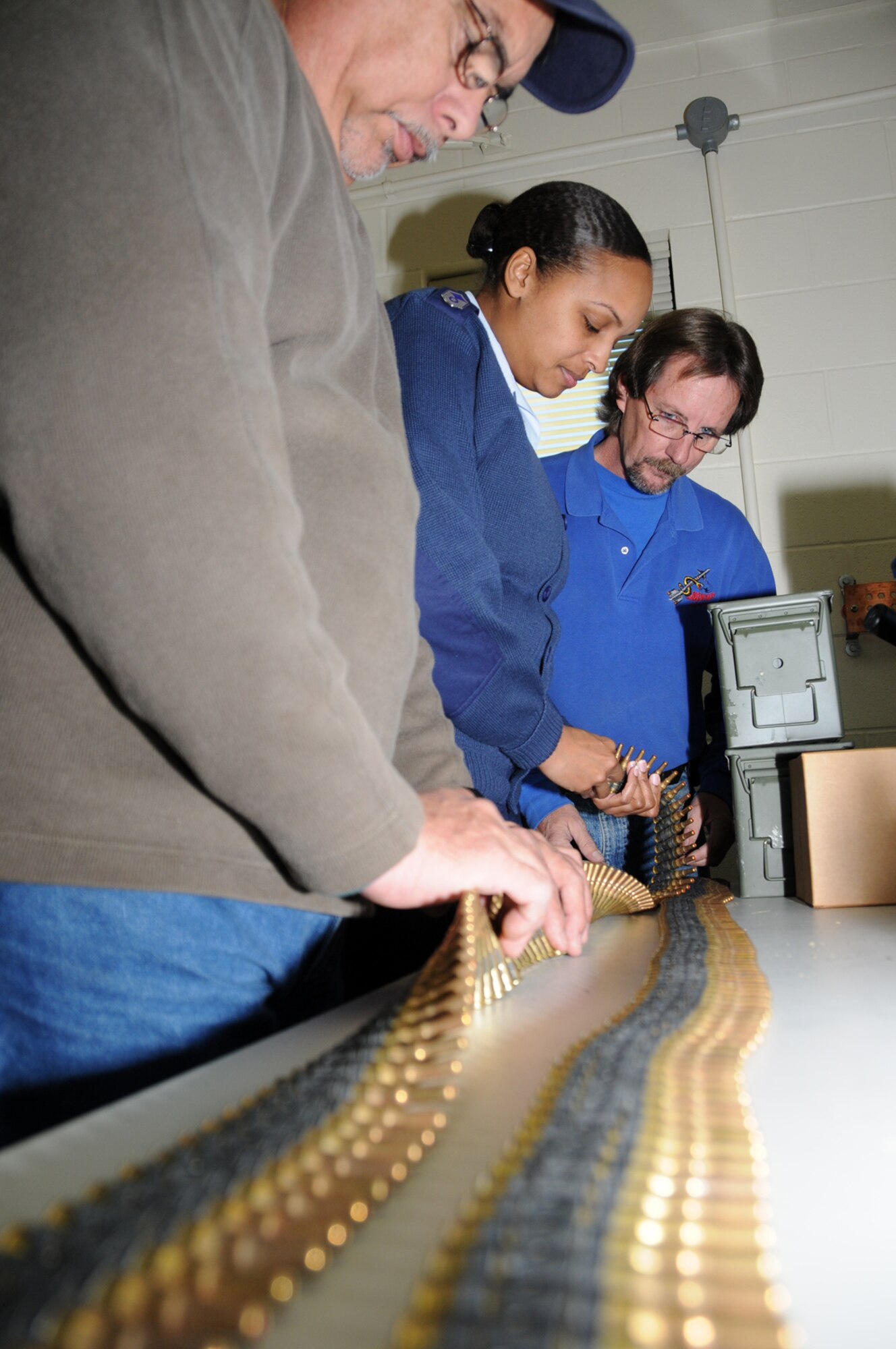 Mr. Mendez and Mr. Brandt conduct a pre-issue ammunition inspection for Master Sgt. Monita McCowan, honor guard manager, inside the maintenance and inspection building at the new facility.  (U.S. Air Force photo by Kemberly Groue)