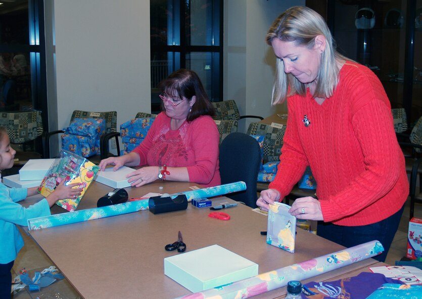 Michaela Waddy, left, talks with Debbie Wardencki, center, about the next gift they will be wrapping as Amy Koncak, right, finishes wrapping another gift at the 505th Training Squadron for the Hurlburt Field Angel Tree Program. Organizers said the 505th TRS’s booster club and the C2 Warrior Fund raised more than $4,000 for presents and clothes for 71 children at both Hurlburt Field and Eglin Air Force Base.  (Courtesy photo)