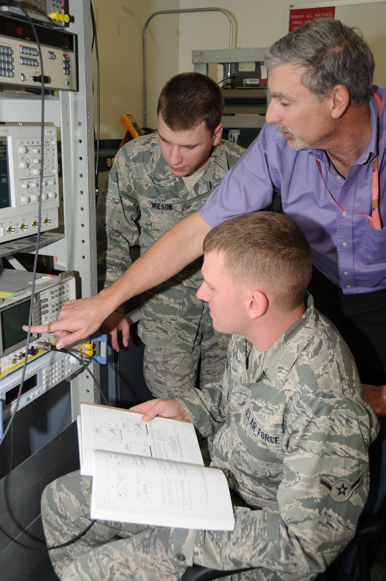 Airman Basic Timothy Wilson, left, and Airman Damon Bitter, seated, watch as 338th TRS instructor Mark Gress explains the basics of an oscilloscope.  (U.S. Air Force photo by Kemberly Groue)
