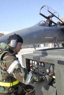 Airman 1st Class Nelson Velez Santiago, an electrical and environmental systems apprentice deployed from Mountain Home Air Force Base, starts the power cart while Staff Sgt. Jason Knight, F-15 Strike Eagle avionics craftsman, also deployed from Mountain Home AFB, performs a maintenance check on the F-15. Both are participating in a Peninsula-wide Operational Readiness Exercise here, Jan. 12. This PENORE ensures that all members are capable of performing their duties in wartime conditions.  (U.S. photo/Staff Sgt. Darnell T. Cannady)