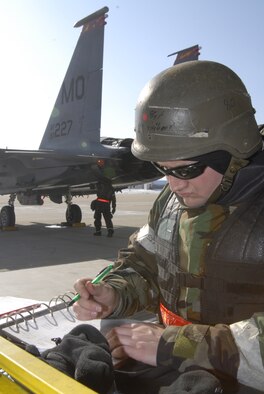 Staff Sgt. Steven Gilbert, a crew chief deployed from Mountain Home Air Force Base, reviews the pre-flight checklist of the F-15 Strike Eagle while Airman 1st Class Nelson Velez Santiago, an electrical and environmental systems apprentice deployed from Mountain Home Air Force Base, inspects the exterior of the F-15. Both members are participating in the Peninsula-wide Operational Readiness Exercise here, Jan. 12. This PENORE ensures that all members are capable of performing their duties in wartime conditions. (U.S. photo/Staff Sgt. Darnell T. Cannady)