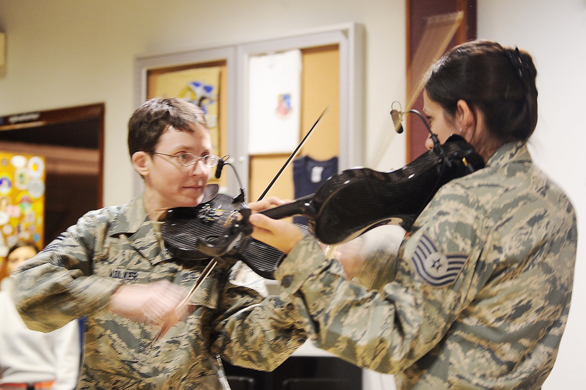 Senior Master Sgt. Deborah Volker (left) and Tech. Sgt. Emily Lewis face off on the violin during a "Celtic Aire" performance at  an air base in Southwest Asia Jan. 7, 2010. The U.S. Air Forces Central band will perform at various locations in the AFCENT area of responsibility during its two-month tour. (U.S. Air Force photo/Senior Airman Kasey Zickmund)