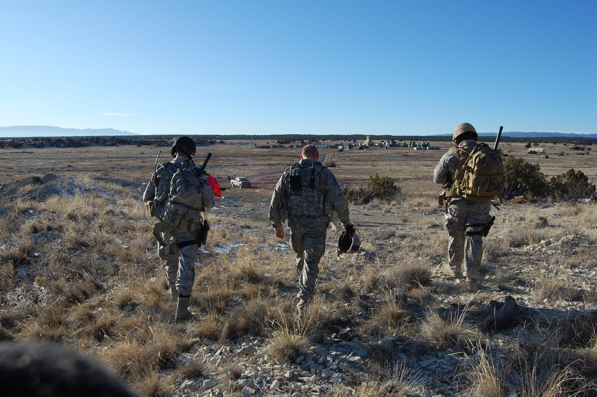 The Joint Terminal Attack Controllers walk to the village after calling in F-16 air strikes.  The two villages on the Airburst Range are created and built by its twelve unit members.