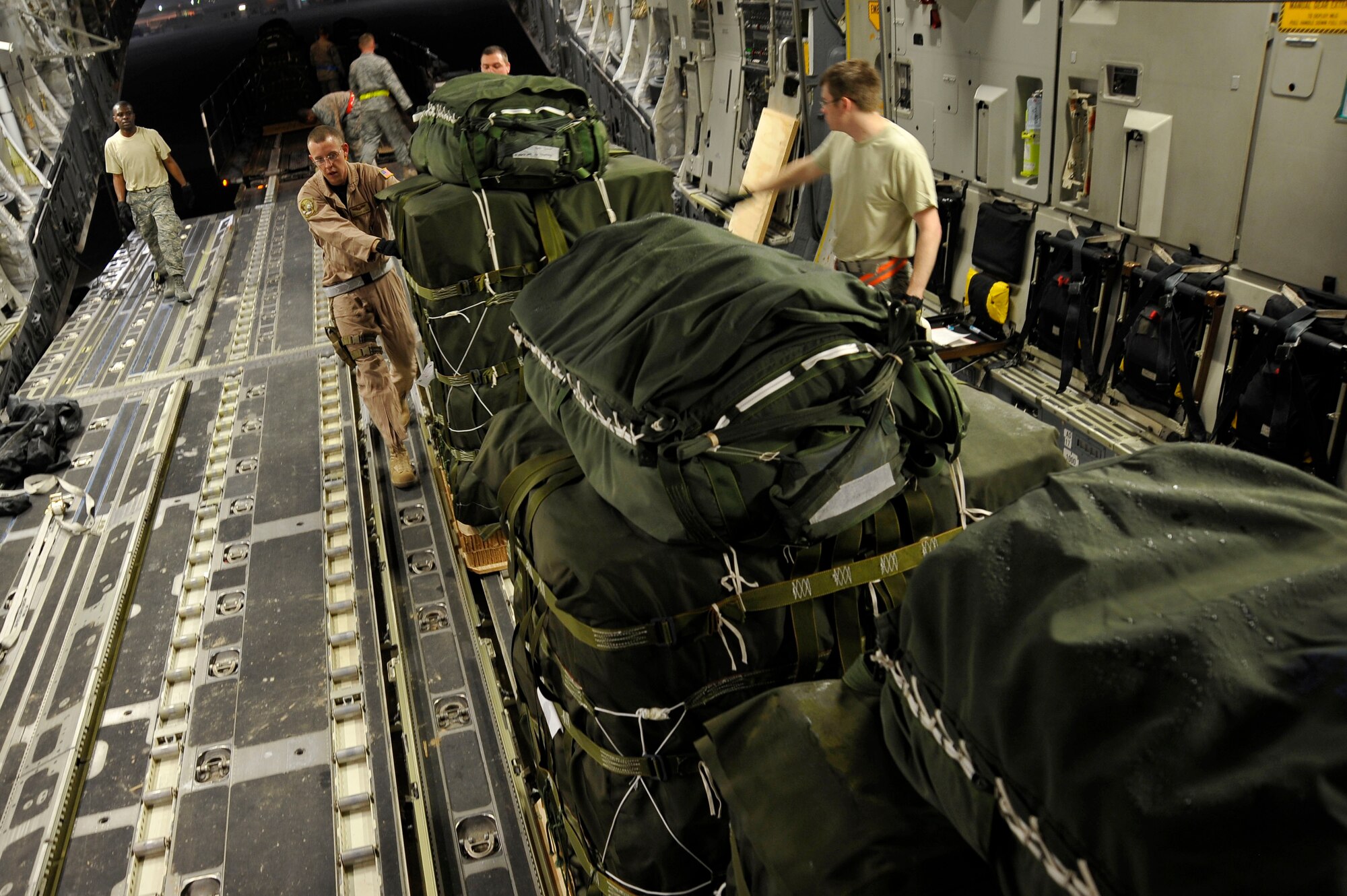 U.S. Air Force Senior Airman Steven Holman, 816th Expeditionary Airlift Squadron loadmaster, pushes a container delivery system bundle onto a C-17 Globemaster III, Jan. 9, 2010, in Southwest Asia.  The CDS bundles will be air dropped to U.S. forces on the ground in Afghanistan. (U.S. Air Force photo/ Staff Sgt. Angelita Lawrence) (released)