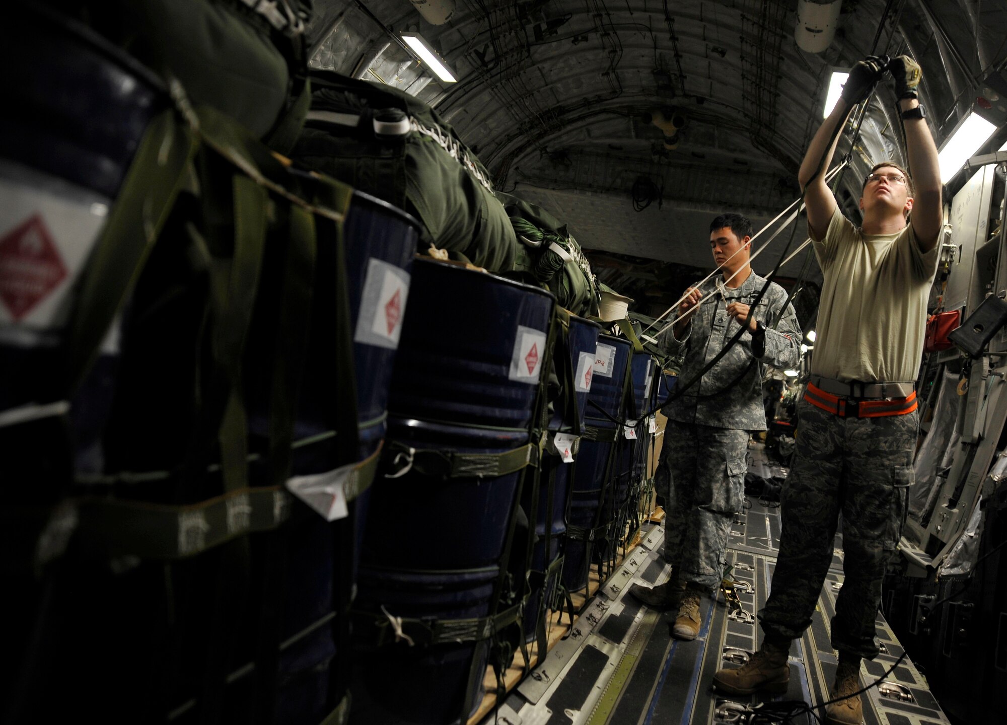 U.S. Air Force Staff Sgt. Marcos Ohler, 816th Expeditionary Airlift Squadron loadmaster, helps  U.S. Army Staff Sgt. Michael Sharp, 824th Quarter Master Company Detachment 8 parachute rigger, prepare parachutes in a C-17 Globemaster III, Jan. 9, 2010, at a deployed location in Southwest Asia. The aircrew will airdrop the container delivery system bundles over a drop zone in Afghanistan to support U.S. ground forces. (U.S. Air Force photo/ Staff Sgt. Angelita Lawrence) (released)