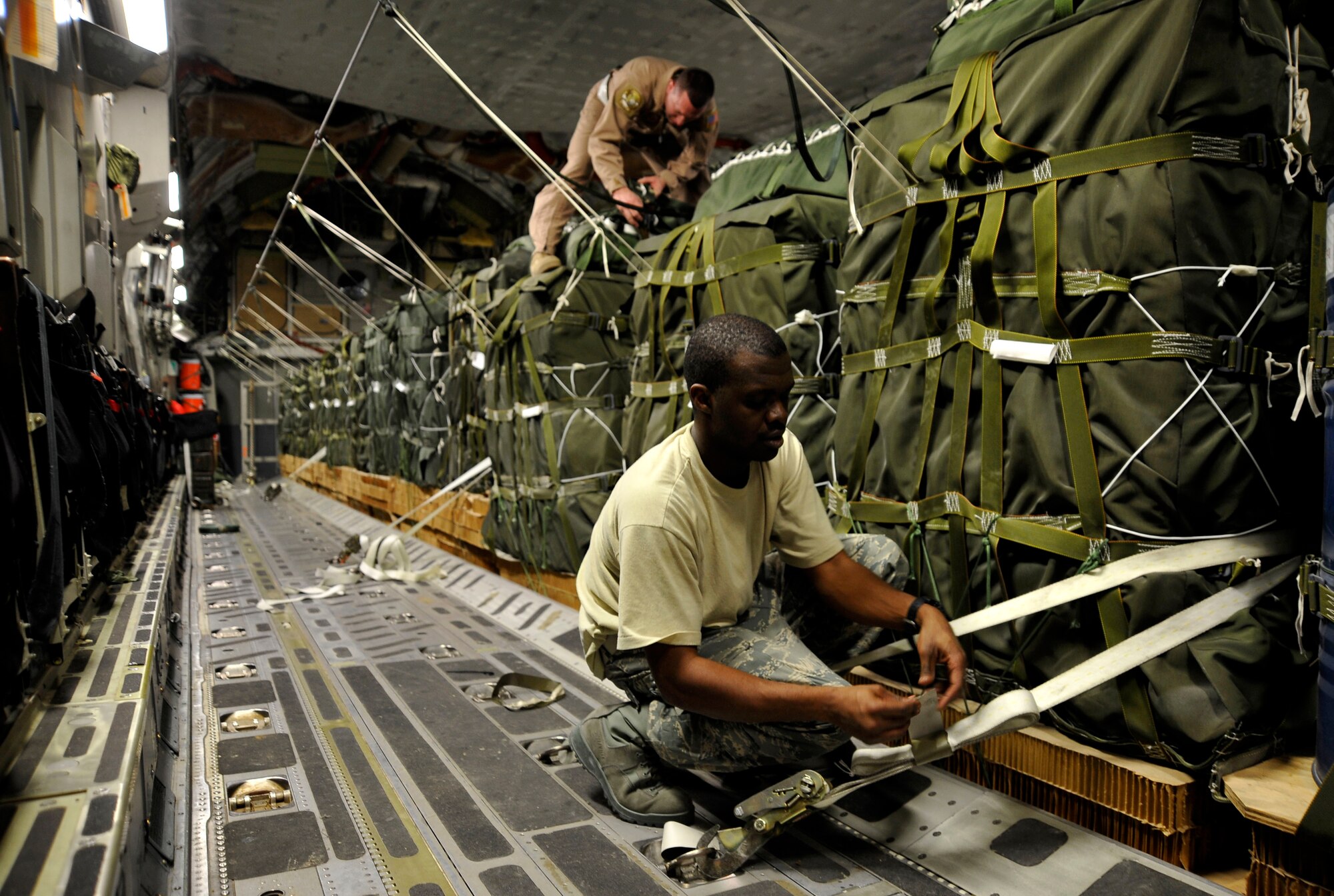U.S. Air Force Senior Airman Albert Taylor, 816th Expeditionary Airlift Squadron loadmaster, secures a container delivery system bundle while Tech. Sgt. Todd O' Bryant, a joint airdrop inspector from the 816th EAS, inspects bundles on board a C-17 Globemaster III at a deployed location in Southwest Asia Jan. 9, 2010.  The CDS bundles will be air dropped to support U.S. forces on the ground in Afghanistan. (U.S. Air Force photo/ Staff Sgt. Angelita Lawrence) (released)