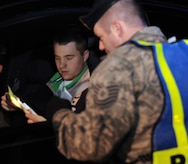 Tech. Sgt. Chad Murphy reviews Airman 1st Class Richard Douglas' license and registration during a mandatory sobriety checkpoint screening at the Dorchester Road main gate in the early morning Jan. 10. The checkpoint was conducted as part of Operation Sober Roads 2 to ensure all individuals entering or exiting Charleston AFB are sober and safe to drive. Sergeant Murphy is the NCO in charge of operations with the 628th Security Forces Squadron, and Airman Douglas is an aircraft maintenance apprentice with the 437th Aircraft Maintenance Squadron. (U.S. Air Force photo/Senior Airman Katie Gieratz)