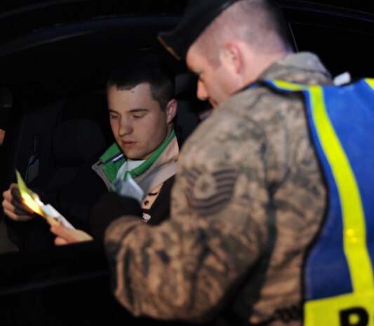 Tech. Sgt. Chad Murphy reviews Airman 1st Class Richard Douglas' license and registration during a mandatory sobriety checkpoint screening at the Dorchester Road main gate in the early morning Jan. 10. The checkpoint was conducted as part of Operation Sober Roads 2 to ensure all individuals entering or exiting Charleston AFB are sober and safe to drive. Sergeant Murphy is the NCO in charge of operations with the 628th Security Forces Squadron, and Airman Douglas is an aircraft maintenance apprentice with the 437th Aircraft Maintenance Squadron. (U.S. Air Force photo/Senior Airman Katie Gieratz)