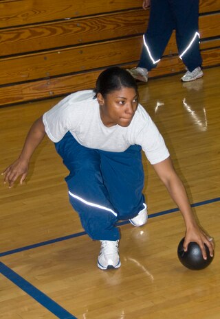 Senior Airman Gina Oliveras grabs up a lose ball while eyeing the air for flying objects during a dodgeball game at the Fitness and Sports Center here Jan. 11. More than 30 students and instructors from the Airman Leadership School and First Term Airmen Center teamed up to hold the game as a fun fitness challenge. Airman Oliveras is an ALS student. (U.S. Air Force photo/Staff Sgt. Daniel Bowles)