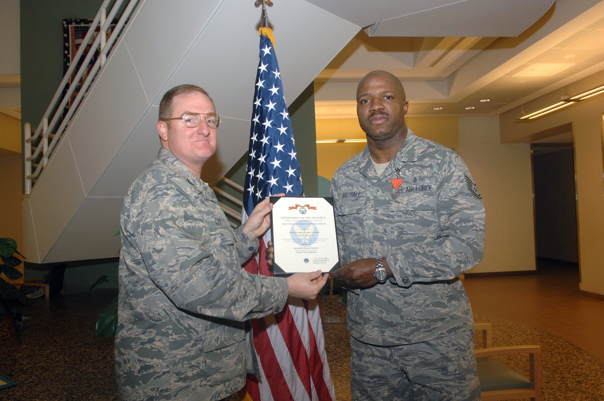 MINOT AIR FORCE BASE, N.D. -- Col. Douglas Cox, 5th Bomb Wing Commander, presents Tech. Sgt. John A. Marshall, 5th Medical Operations Squadron personnel reliability program flight management noncommissioned officer-in-charge, with the Air Force Combat Action Medal here Jan 6. Sergeant Marshall received the medal when he was deployed to Kandahar, Afghanistan, attached to a NATO combat battalion as the only medic where he engaged hostile enemy forces and helped to treat wounded troops as well as returned fire. The principal eligibility criterion to receive the medal is that the individual must have been under direct and hostile fire while operating in unsecured space (outside the defended perimeter), or physically engaging hostile forces with direct and lethal fire. (U.S. Air Force photo by Senior Airman Jesse Lopez)