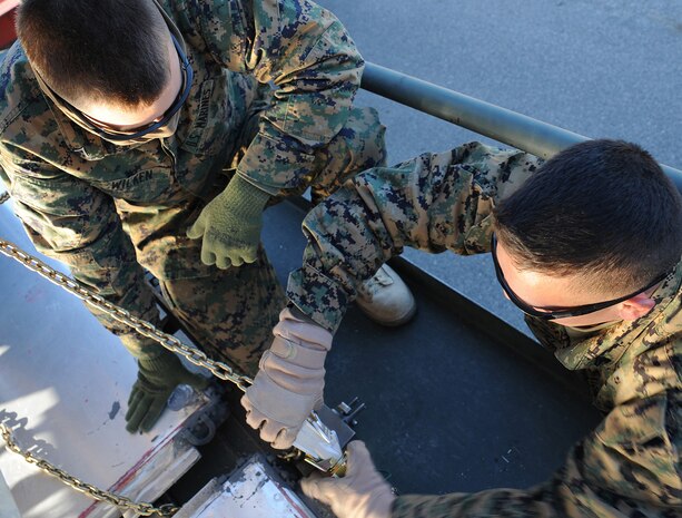 Marine Cpl. Matt Netzel assists Marine Lance Cpl. Justin Wilken in tying down a mine-resistant, ambush-protected all-terrain vehicle to a support pallet here Jan. 5. The two Marines are part of a team who operates out of Charleston AFB to assist in preparing M-ATVs for shipment. Corporals Netzel and Wilken are landing support specialists with the 4th Landing Support Battalion. (U.S. Air Force photo/Senior Airman Katie Gieratz)(RELEASED)
