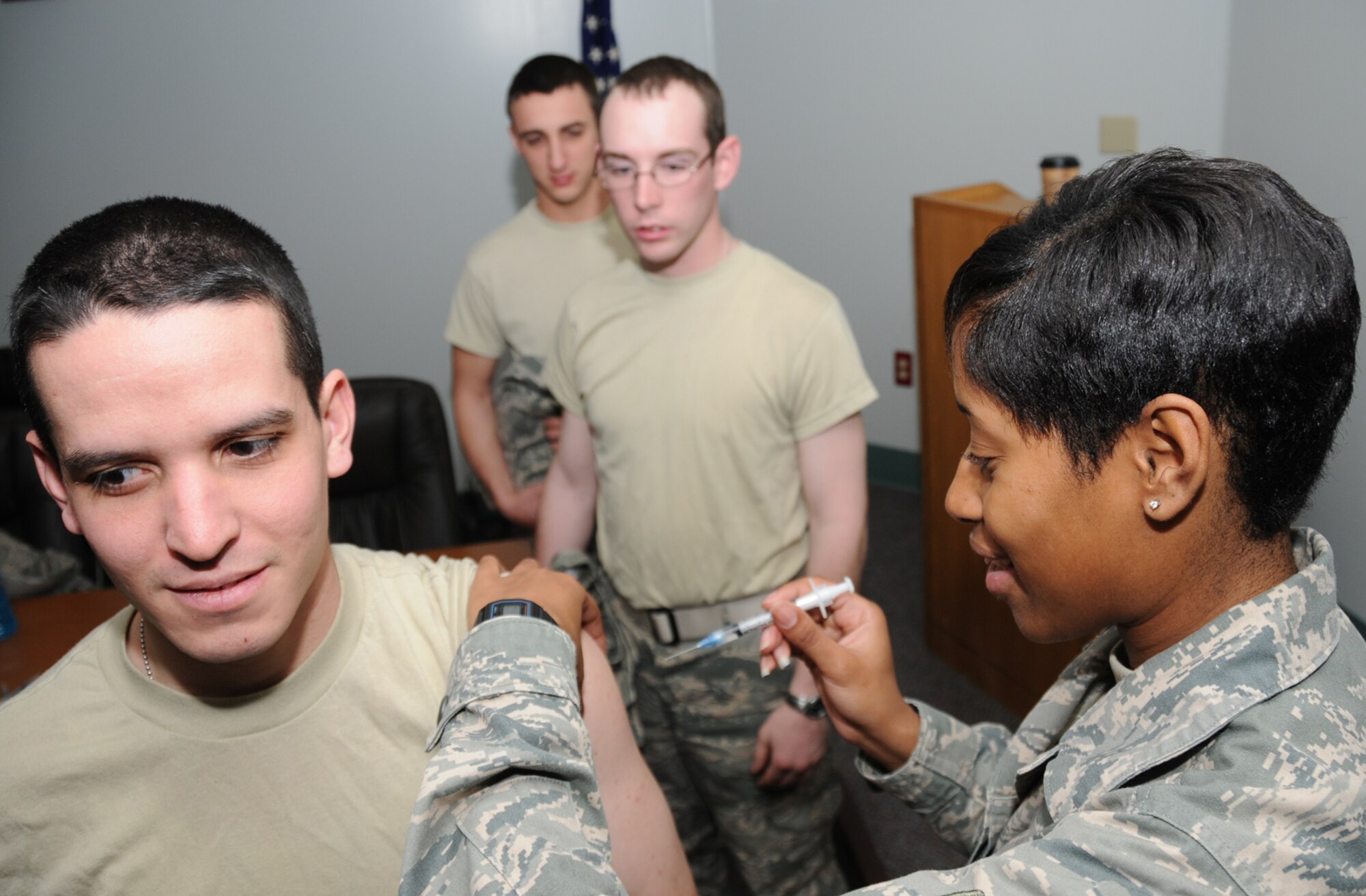 Airman 1st Class Nicholas Brazeau, left, 332nd Training Squadron student, receives a H1N1 vaccination from Airman 1st Class Shanika Stewart, 81st Medical Support Squadron, at Dolan Hall Tuesday as fellow 332nd TRS students Airmen Paul Tumpson and Jeremy Caton wait their turn.  Active-duty military are required to receive both H1N1 and seasonal flu shots.  (U.S. Air Force photo by Kemberly Groue)