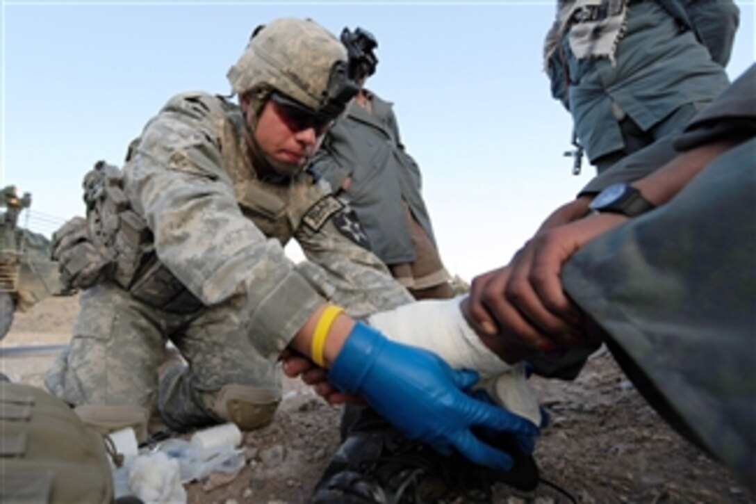 U.S. Army Spc. Luis Cabrales, with 8th Squadron, Bear Troop, 1st Cavalry Regiment, provides medical aid to an injured Afghan National Police officer near Dabaray, Afghanistan, on Jan. 3, 2010.  