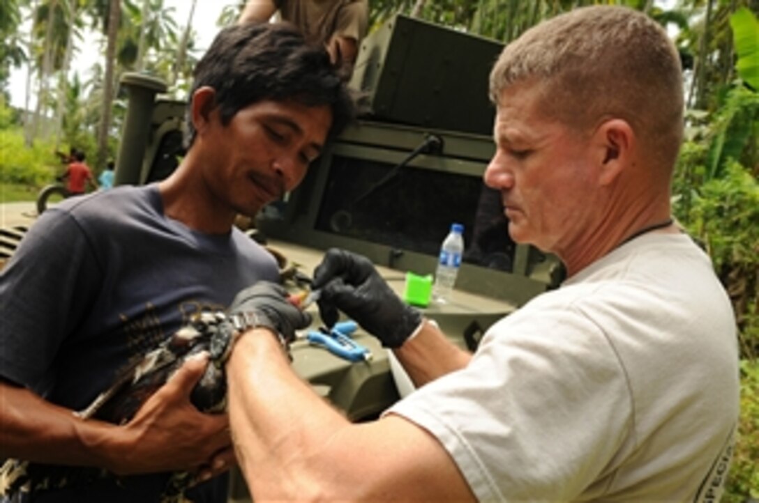 U.S. Army Lt. Col. Steven Goldsmith (right), a veterinarian with Joint Special Operations Task Force-Philippines, administers de-worming medicine to a chicken during a medical and veterinary civic action program in Sulu, Philippines, on Jan. 7, 2010.  Health officials treated more than 130 patients and 31 animals during the program.  