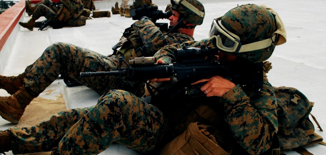 Embedded Training Team members Seaman Christopher Gonzales, front, and Sgt. Anthony Moran observe with unloaded weapons from their post atop the 4th Marine Regiment Headquarters Building on Camp Schwab during a portion of the Combat Hunter Course Jan. 7-15.