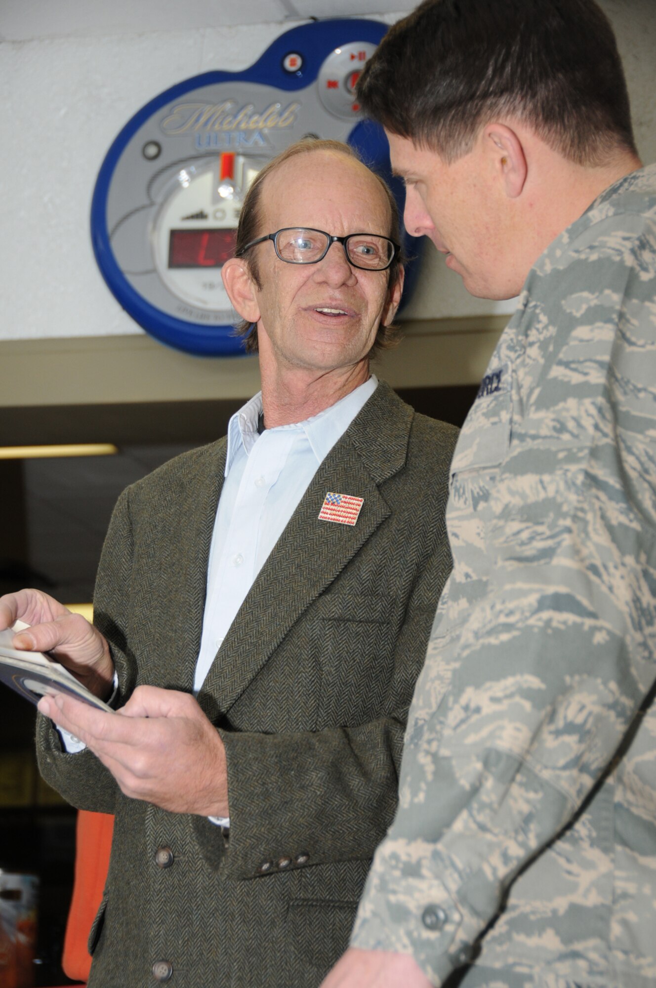 Terry Janca, left, shows some photos from the Gaudé family archives to Brig. Gen. Ian Dickinson at a ribbon cutting for the remodeled Gaudé Lanes Bowling Center Jan. 12.  Mr. Janca is the godson of the late Tonsie Gaudé, mother of 1st Lt. Robert Gaudé of Biloxi, for whom the bowling center is named.  Lieutenant Gaudé, an F-84 pilot, died in combat over North Korea in 1953.  (U.S. Air Force photo by Kemberly Groue)