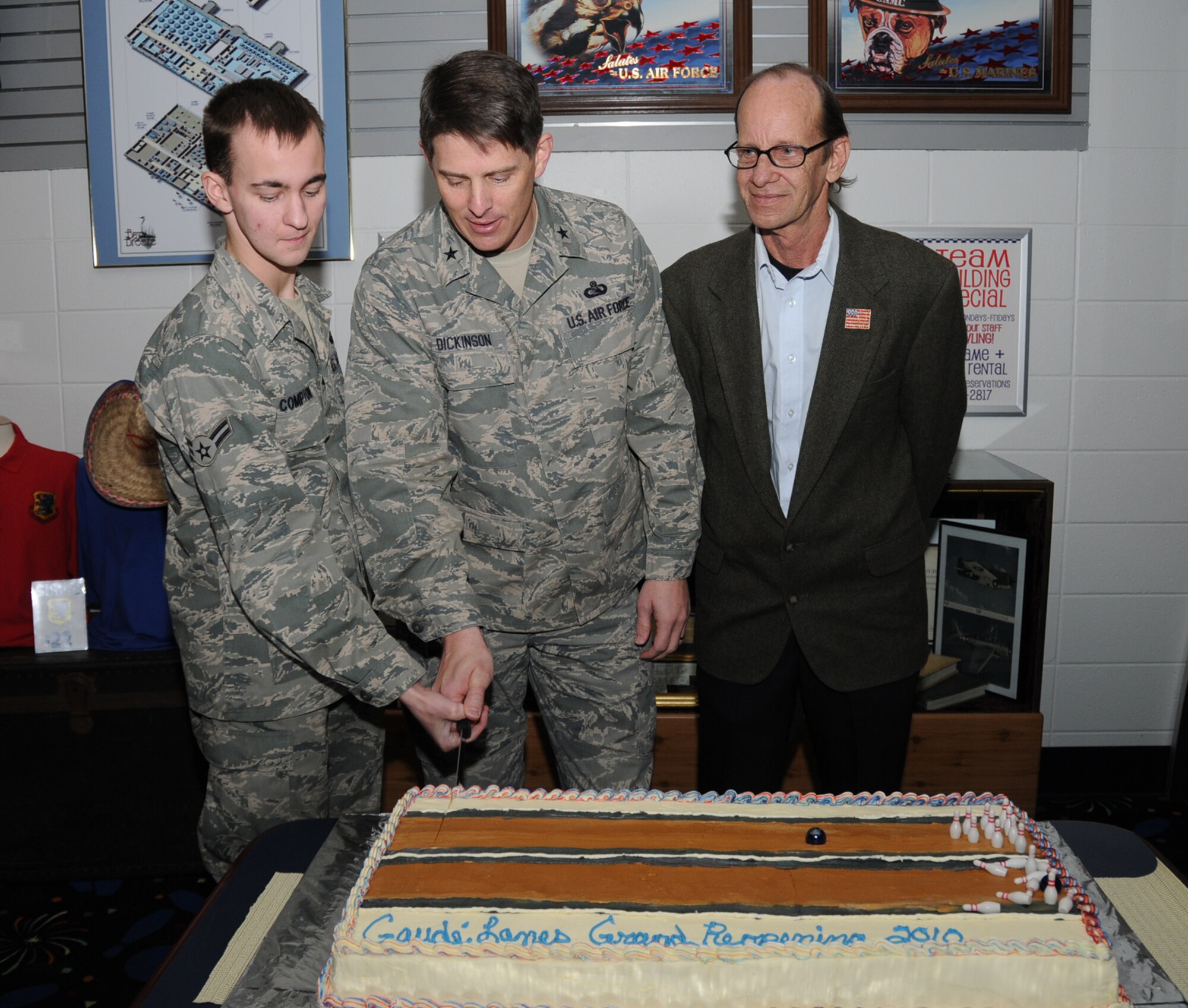 left, Airman 1st Class Evan Compton, 81st Force Support Squadron; Brig. Gen. Ian Dickinson, 81st Training Wing commander, and Terry Janca, representing the Gaudé family, and Brig. Gen. Ian Dickinson, 81st Training Wing commander, cut the cake at the reopening of the Gaudé Lanes Bowling Center Jan. 12.  (U.S. Air Force photo by Kemberly Groue)