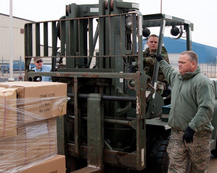 Senior Airman Sean Martin (forklift) and Master Sgt. Warren Bartee (guiding), both of the 136th Logistics Readiness Squadron, load 5,000 water filtration systems on to a pallet for load planning, Jan. 14, 2010 at NAS Fort Worth JRB, Carswell Field, Texas. The filtration systems were donated by the Texas Baptist Men to aid in the relief effort in Haiti. (U.S. Air Force Photo/Senior Airman Andrew Dumboski/Released)