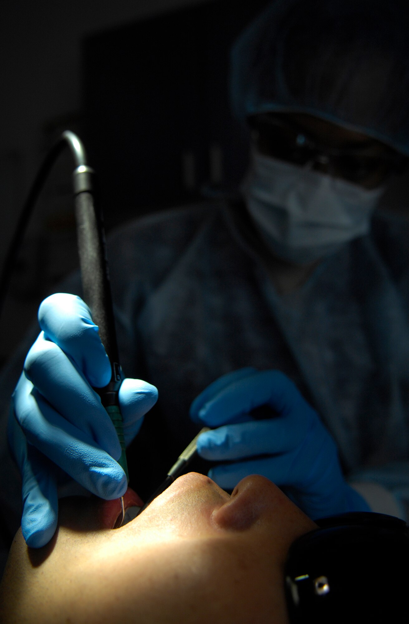 VANDENBERG AIR FORCE BASE, Calif. --  While working in the dark, Staff Sgt. Asia Nettles, a dental assistant craftsman from the 30th Medical Operations Squadron here, cleans the teeth of Capt. Chris Sakamoto, from the 533rd Training Squadron here, with a cavitron water pick during an annual dental cleaning here Tuesday, Jan. 12, 2010.   (U.S. Air Force photo/Airman 1st Class Andrew Lee)