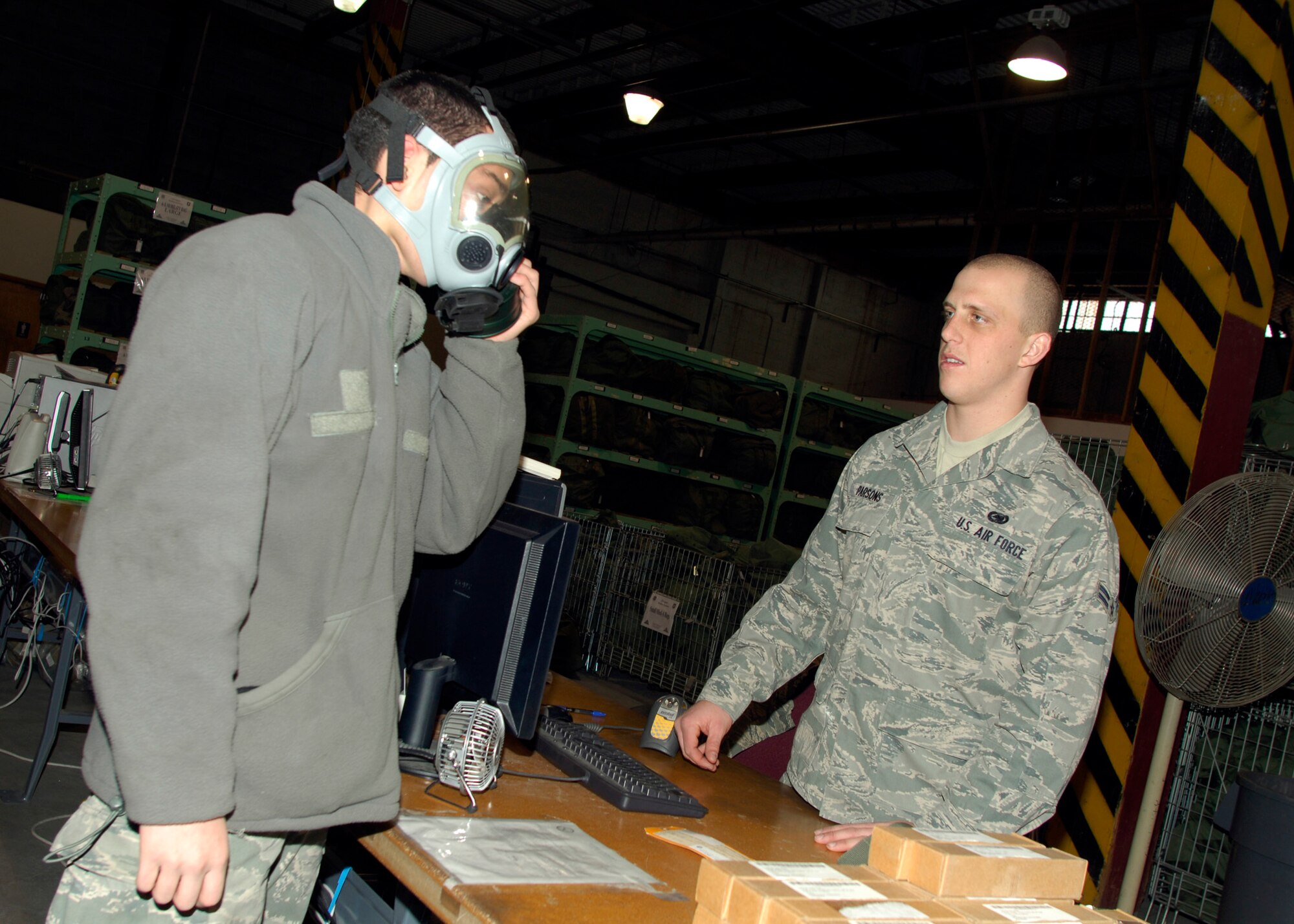 Airman 1st Class Dustin Parsons, 22nd Logistics Readiness Squadron supply journeyman, issues a gas mask to Airman 1st Class Julio Guerrero-Hernandez, 22nd Maintenance Squadron KC-135 Stratotanker crew chief, in the supply building, Jan. 5, 2010, at McConnell Air Force Base, Kan. Upon arrival to McConnell, all Airmen must process through supply to be issued a gas mask for exercises and deployments. (U.S. Air Force photo/Staff Sgt. Anthony Mejia)