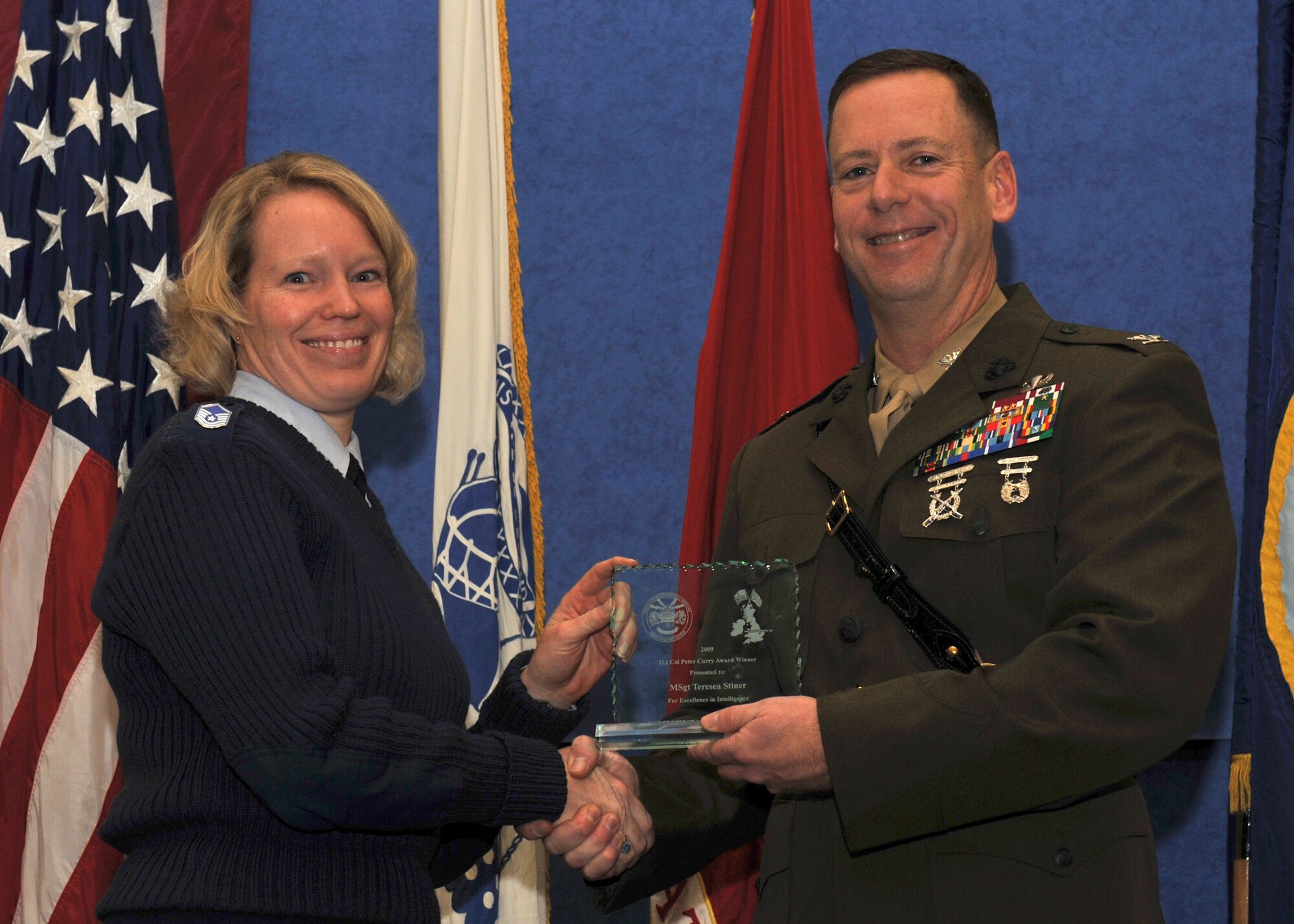 Air Force Master Sgt. Teresea M. Stiner is presented the 1Lt. Peter Curry Award by JIOCEUR Analytic Center Commander, Marine Corps Col. Pete Devlin.  The award recognizes the enlisted professional who made the most significant contribution to the accomplishment of the JAC mission.  The winner of  the Lt Col Carlton Smith Award, Ms. Anne W. Buelow was not present for the award (U.S. Air Force photo by Staff Sgt.  Javier Cruz)