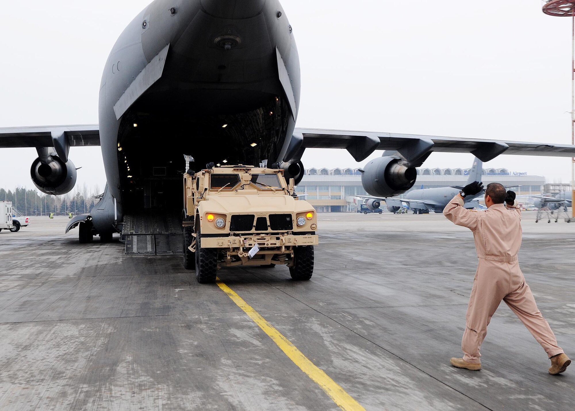 Tech. Sgt. Antonio Munoz, NCOIC and instructor loadmaster from the Transit Center's C-17 detachment, guides an mine-resistant, ambush-protected (MRAP) vehicle into a C-17 Globemaster III prior to shipment to Afghanistan at the Transit Center at Manas, Kyrgyzstan. The new M-ATVs are better equipped to withstand current combat conditions. Several C-17s provide airlift for military servicemembers and cargo. (U.S. Air Force photo by Senior Airman Nichelle Anderson/released)
