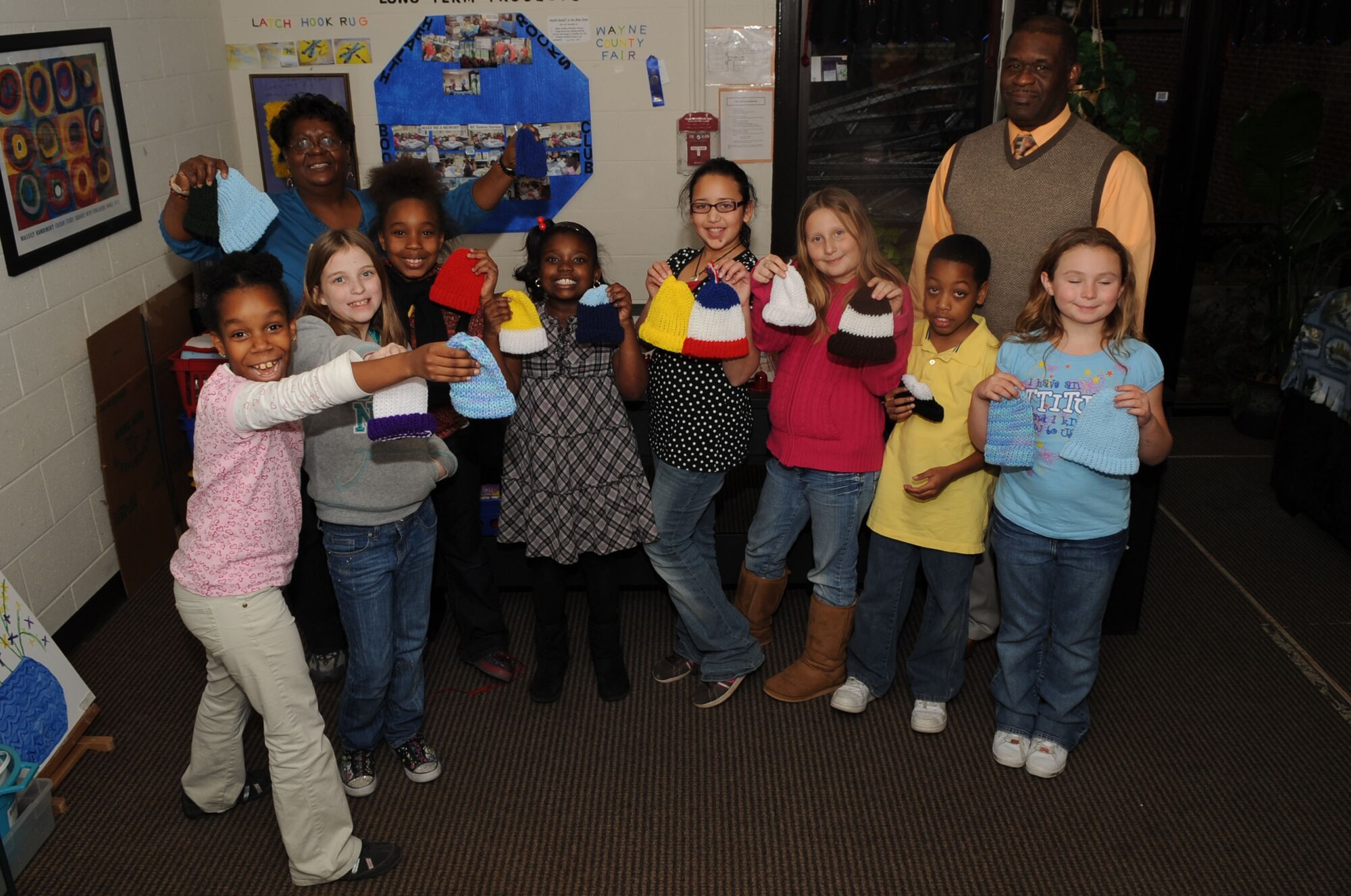 Children from the school-age program on Seymour Johnson Air Force Base, N.C., pose for a photo with William Jenkins, Bundles for Babies coordinator, at the youth center, Jan. 12, 2010. The school-age program, open to children ages 9-12, offers a number of community service projects for children to participate in throughout the year. Last summer the children decided to make knit hats for the Bundles for Babies program. (U.S. Air Force photo/Staff Sgt. Courtney Richardson)