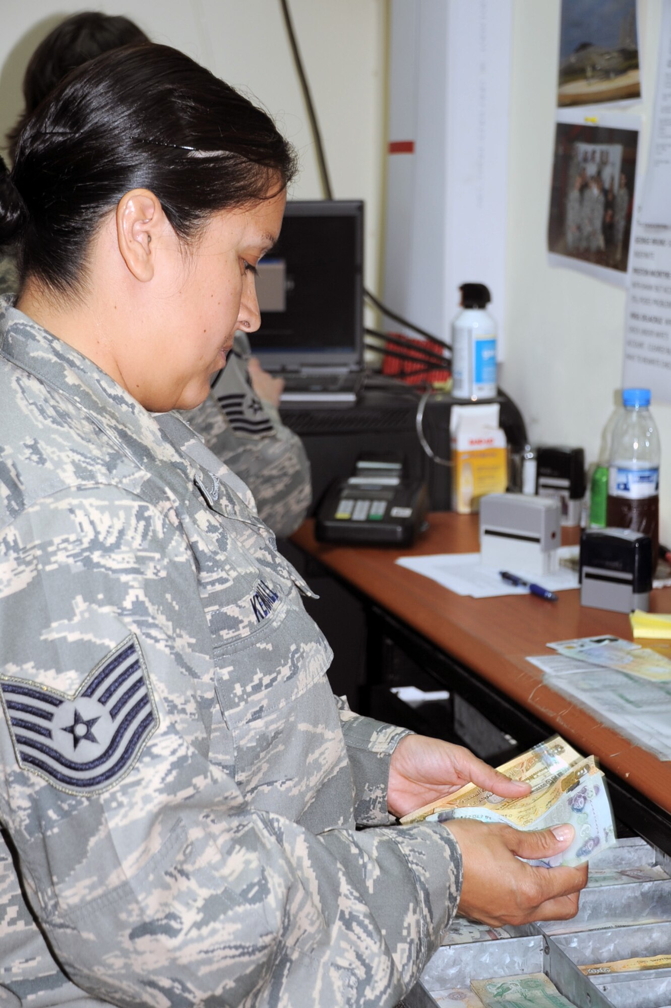 Tech. Sgt. Diana Kendall of the 380th Air Expeditionary Wing financial management office exchanges money at her office's cashier's cage during operations Jan. 8, 2009, at a non-disclosed base in Southwest Asia.  Sergeant Kendall is deployed from the 919th Special Operations Wing at Duke Field, Fla., and her hometown is San Antonio, Texas.  (U.S. Air Force Photo/Tech. Sgt. Scott T. Sturkol/Released)