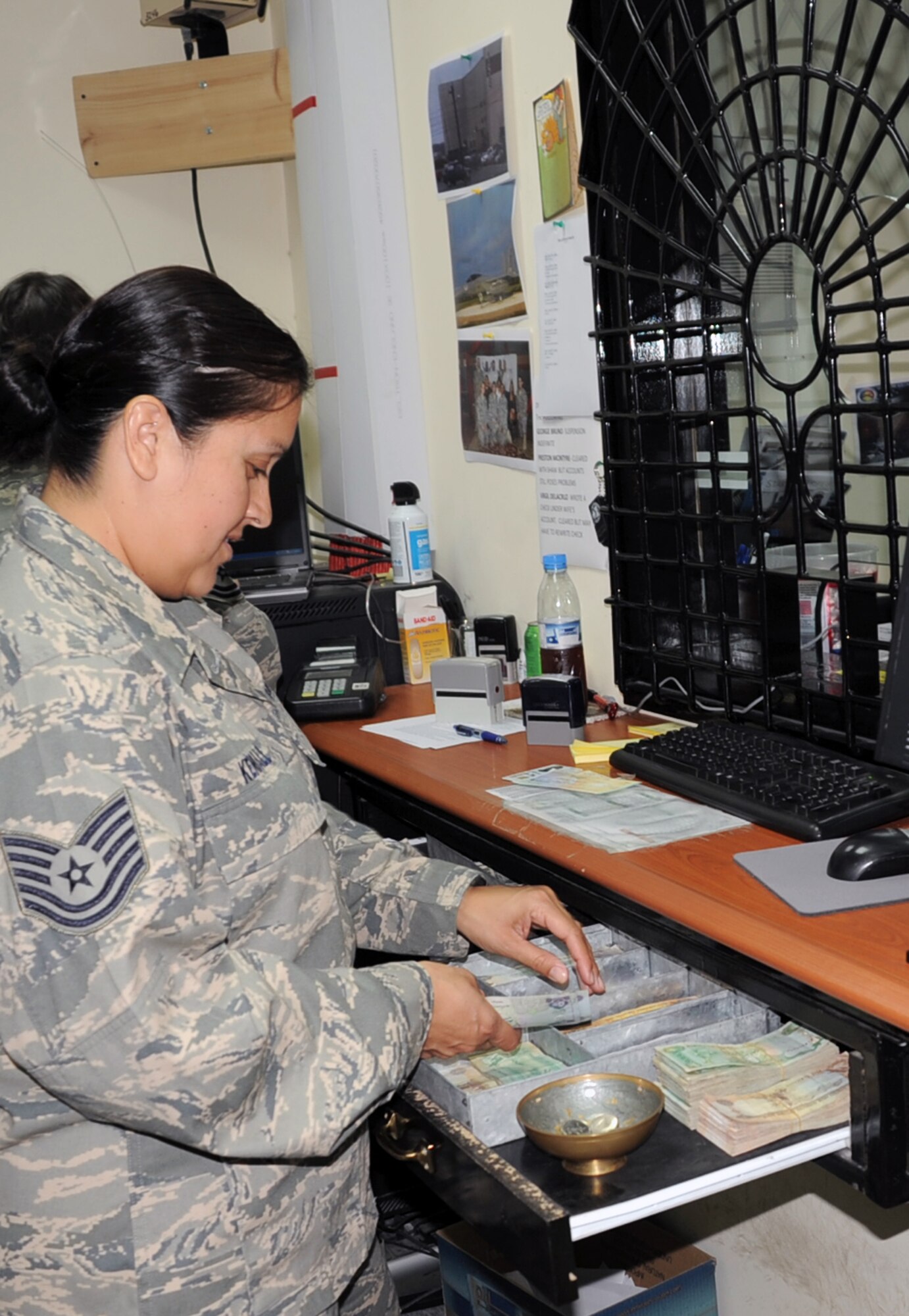 Tech. Sgt. Diana Kendall of the 380th Air Expeditionary Wing financial management office exchanges money at her office's cashier's cage during operations Jan. 8, 2009, at a non-disclosed base in Southwest Asia.  Sergeant Kendall is deployed from the 919th Special Operations Wing at Duke Field, Fla., and her hometown is San Antonio, Texas.  (U.S. Air Force Photo/Tech. Sgt. Scott T. Sturkol/Released)