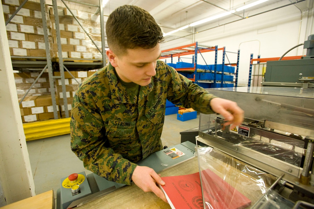 Lance Cpl. Zackery Strong, warehouse clerk, Marine Corps Institute, loads a textbook into the shrink wrap machine at the MCI warehouse at the Washington Navy Yard in Washington, D.C., Jan 14. The processed textbooks are then sorted into bins, where they are ready to be swiftly loaded onto a conveyor belt at the beginning of the shipping run each day.