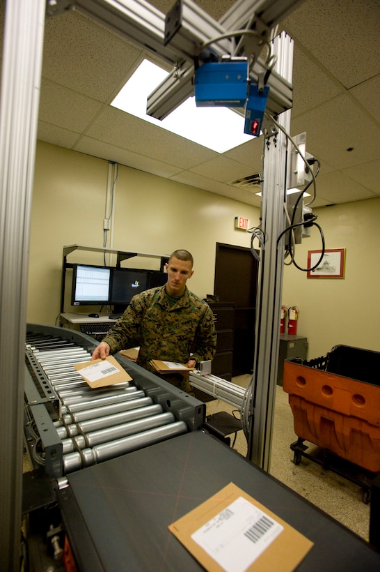 Cpl. Corey Quill, Marine Corps Institute postal clerk, loads MCI course examinations onto the final portion of the conveyor belt, where they are sorted into mailing bags. Paper-based examinations are too light to move across some portions of the belt.