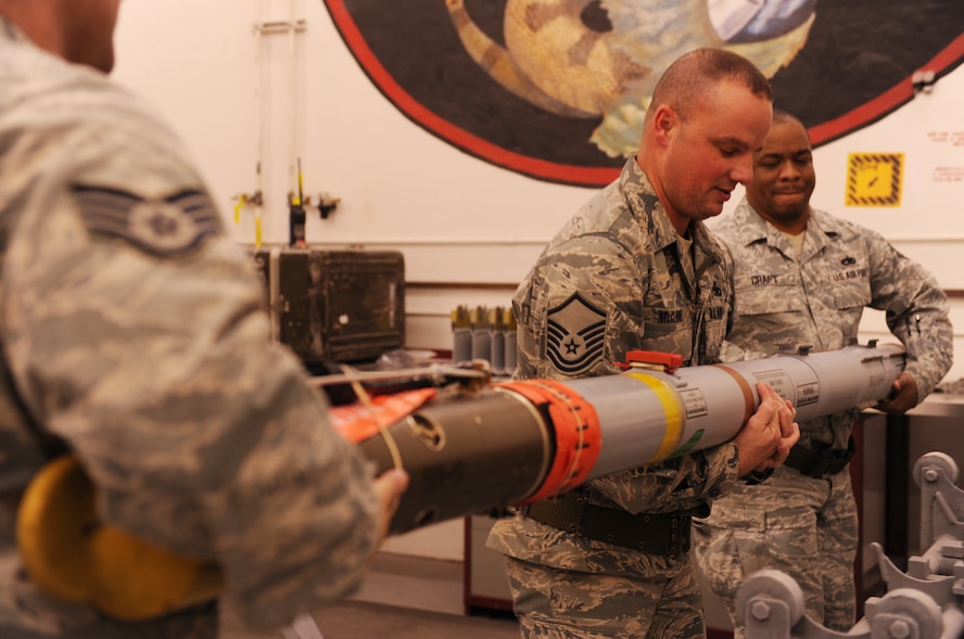 MOODY AIR FORCE BASE, Ga. -- Master Sgt. Jeff McClure, 23rd Equipment Maintenance Squadron munitions precision guided missile NCO in-charge, works with Tech. Sgt. Mario Craft, 23rd EMS munitions PGM crew chief, and Staff Sgt. David Sain, 23rd EMS munitions flight PGM inspector, to lift a short-range missile from the stand during a Phase I Operational Readiness Exercise here Jan. 11. The sidewinder missile weighs 191 pounds and requires three people to life safely. (U.S. Air Force photo by Airman 1st Class Benjamin Wiseman)