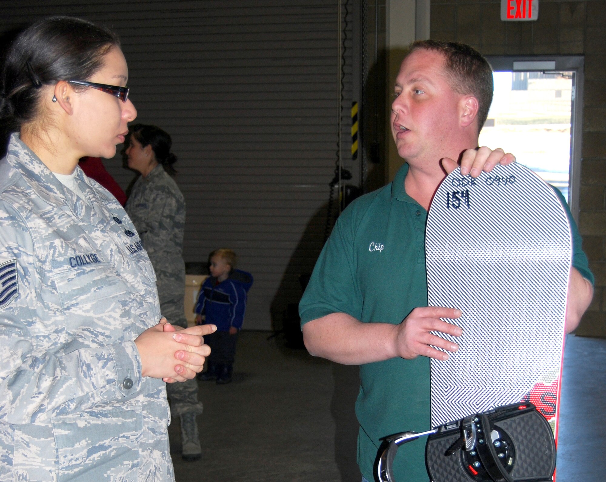 Tech. Sgt Kimberly Collyge, Equal Opportunity non-commissioned officer in charge, asks Chip Davis, Outdoor Recreation small engine mechanic, about snowboarding and some of the new Outdoor Recreation equipment and programs at the Outdoor Recreation Open House Dec. 17, 2009.