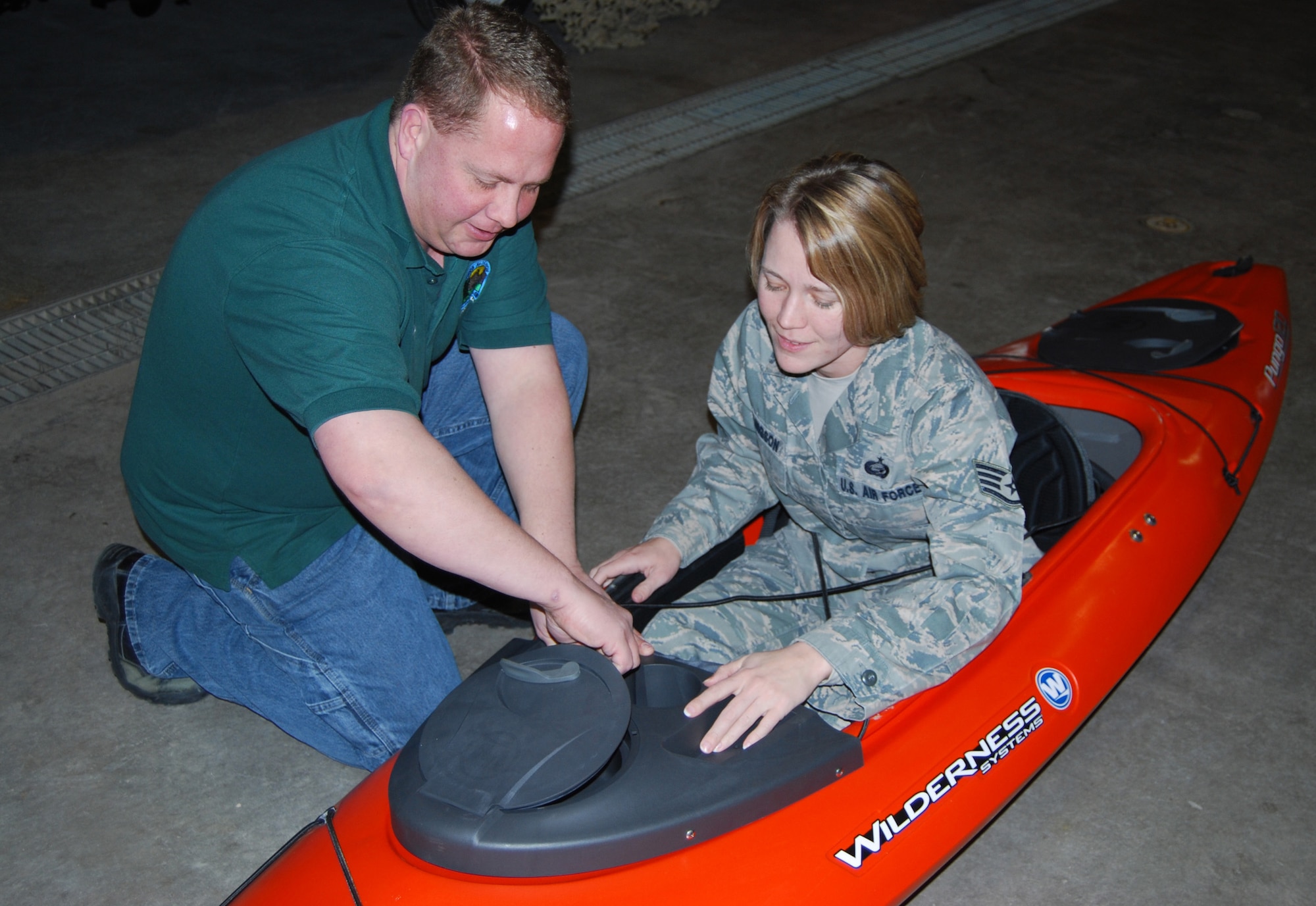 Chip Davis shows Staff Sgt. Joelle Ellingson, 341st Force Support Squadron IDEA Analyst, how the new touring kayaks work during the Outdoor Recreation Open House Dec.  17, 2009. Kayaking is just one of many sports the staff at Outdoor Recreation is knowledgable in and can assist new patrons with learning. (U.S. Air Force photos/Airman 1st Class Kristina Overton)