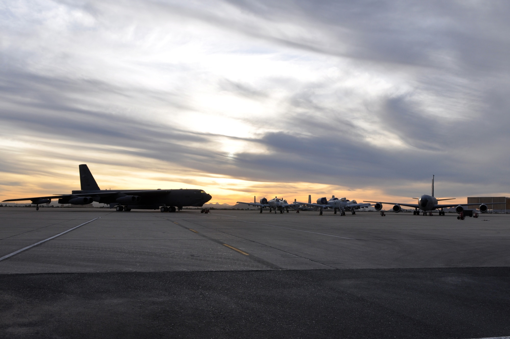 As the sun sets, a B-52 Stratofortess stands opposite a group of A-10 Thunderbolt IIs and a KC-135 Stratotanker on Davis-Monthan Air Force Base, Ariz., on Jan. 6, 2010. The aircraft were set up to be used as displays and transportation for the 45th Fighter Squadron reactivation ceremony on Davis-Monthan January 7, 2010. The reactivation of the historic unit brought the squadron back into the A-10 Thunderbolt II community. Current members, retirees and distinguished visitors witnessed the ceremony. (U.S. Air Force photo/Tech. Sgt. Jeffery Walston)