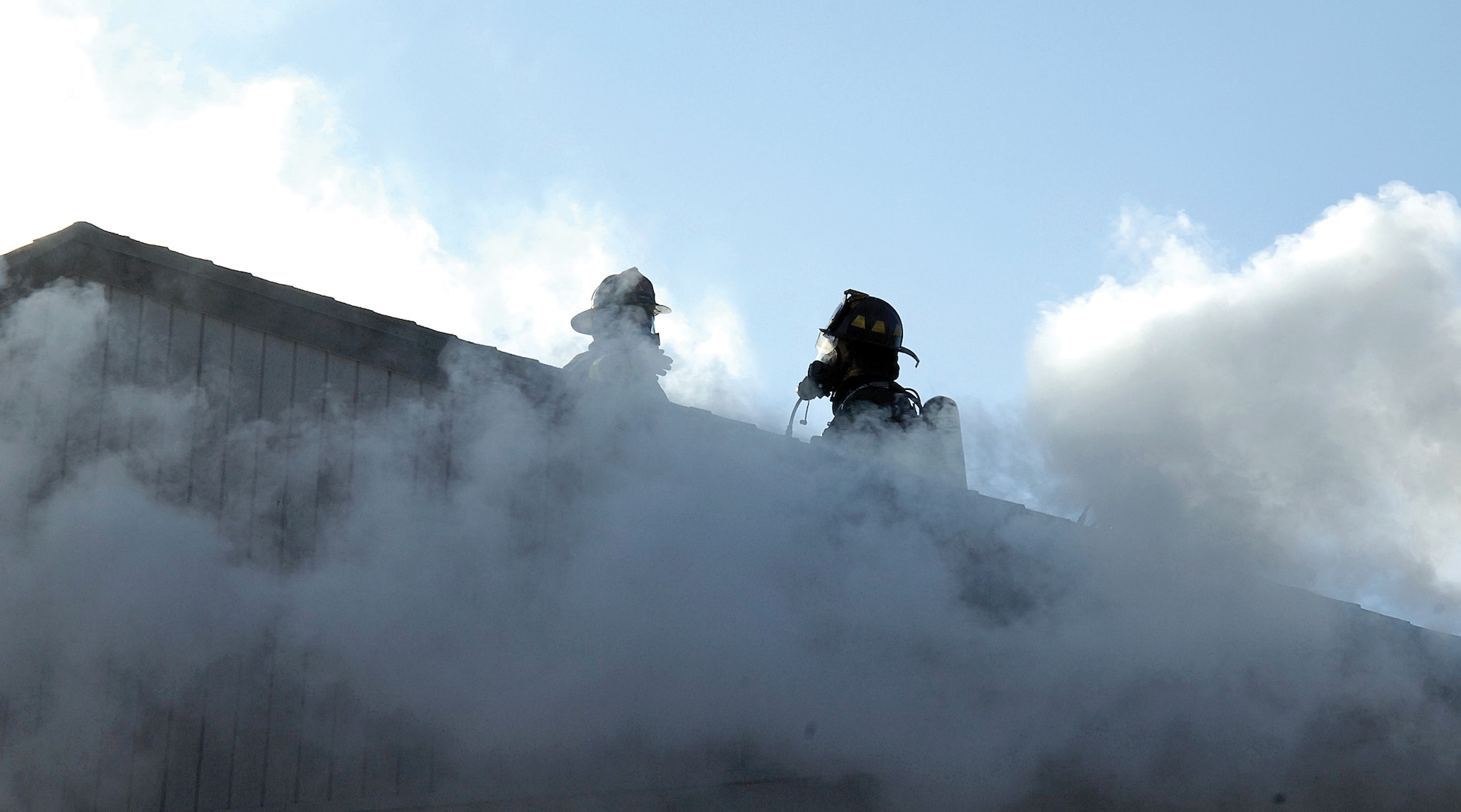 Smoke and steam swirl upwards, engulfing a Tinker Fire Department ventilation team who helps firefighters inside the structure by punching holes in the roof releasing heat, gases and smoke when needed. (Air Force photos by Margo Wright)