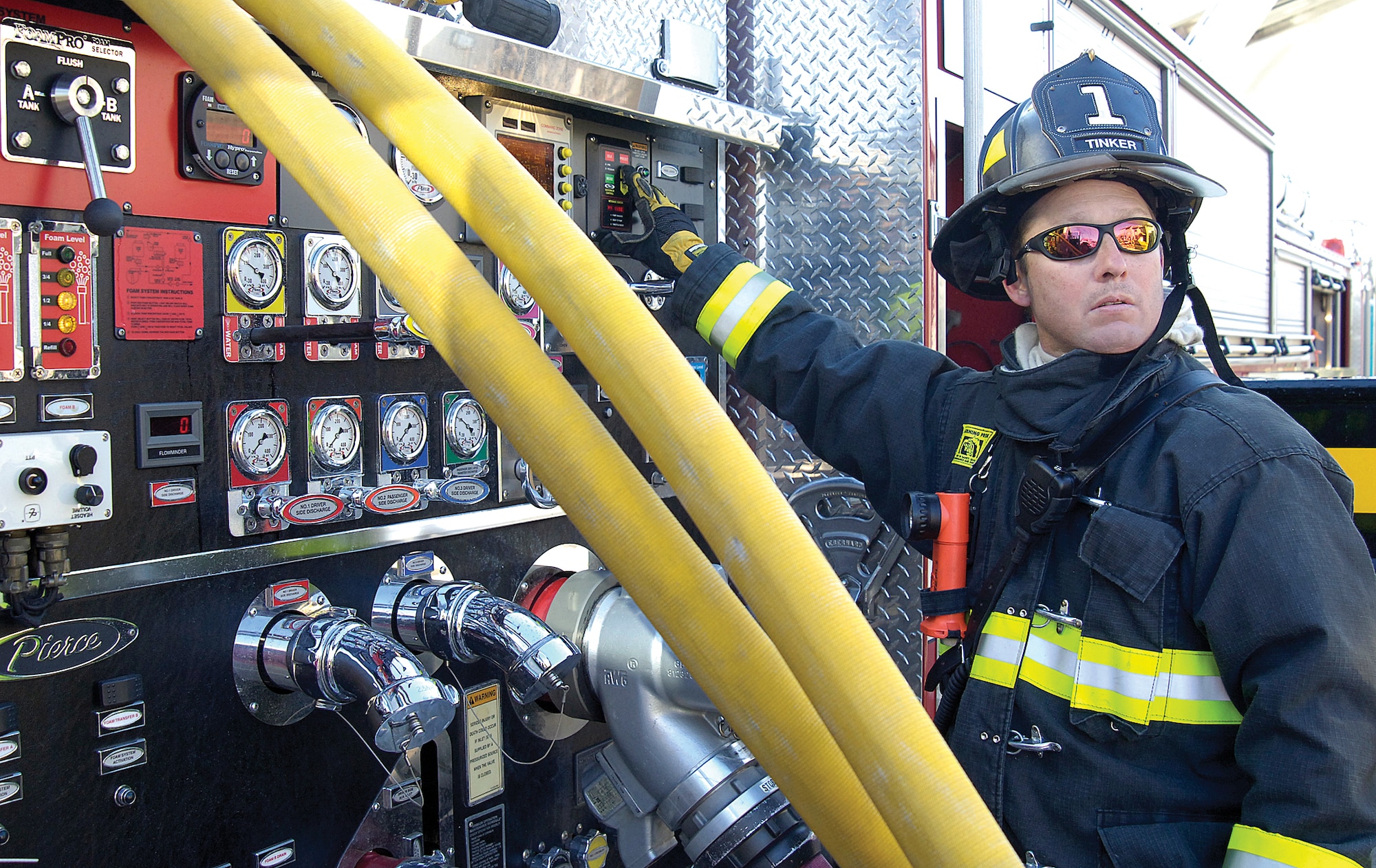 Tinker firefighter Chad Beals keeps an eye on fellow firefighters entering the smoke-filled structure, providing correct water pressure to the hose from the truck nearby. One hundred pounds of pressure fills the lines that firefighters handle while staying low and hefting more than 50 pounds of protective gear into a burning structure. (Air Force photos by Margo Wright)