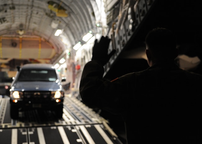 Master Sgt. Michael Lang marshals a sport utility vehicle off of a Charleston AFB C-17 in Port-au-Prince, Haiti, Jan. 15, 2010. Air Mobility Command is responding with all necessary forces and equipment to aide the humanitarian efforts in Haiti. Sergeant Lang is a loadmaster with the 317th Airlift Squadron. (U.S. Air Force photo/Senior Airman Katie Gieratz)(RELEASED)