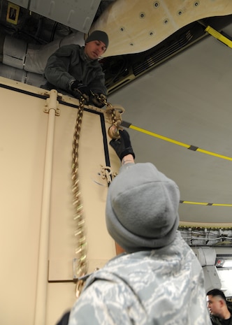 Tech. Sgt. Jeremy Morris and Senior Airman Christopher Williams chain down a mobile command and control unit onto a Charleston C-17 at Joint Base McGuire-Dix-Lakehurst, New Jersey, Jan. 15, 2010. The Charleston C-17 was used to transport equipment needed to aid the humanitarian effort in Haiti. Sergeant Morris and Airman Williams are with the 305th Aerial Port Squadron. (U.S. Air Force photo/Senior Airman Katie Gieratz)(RELEASED)