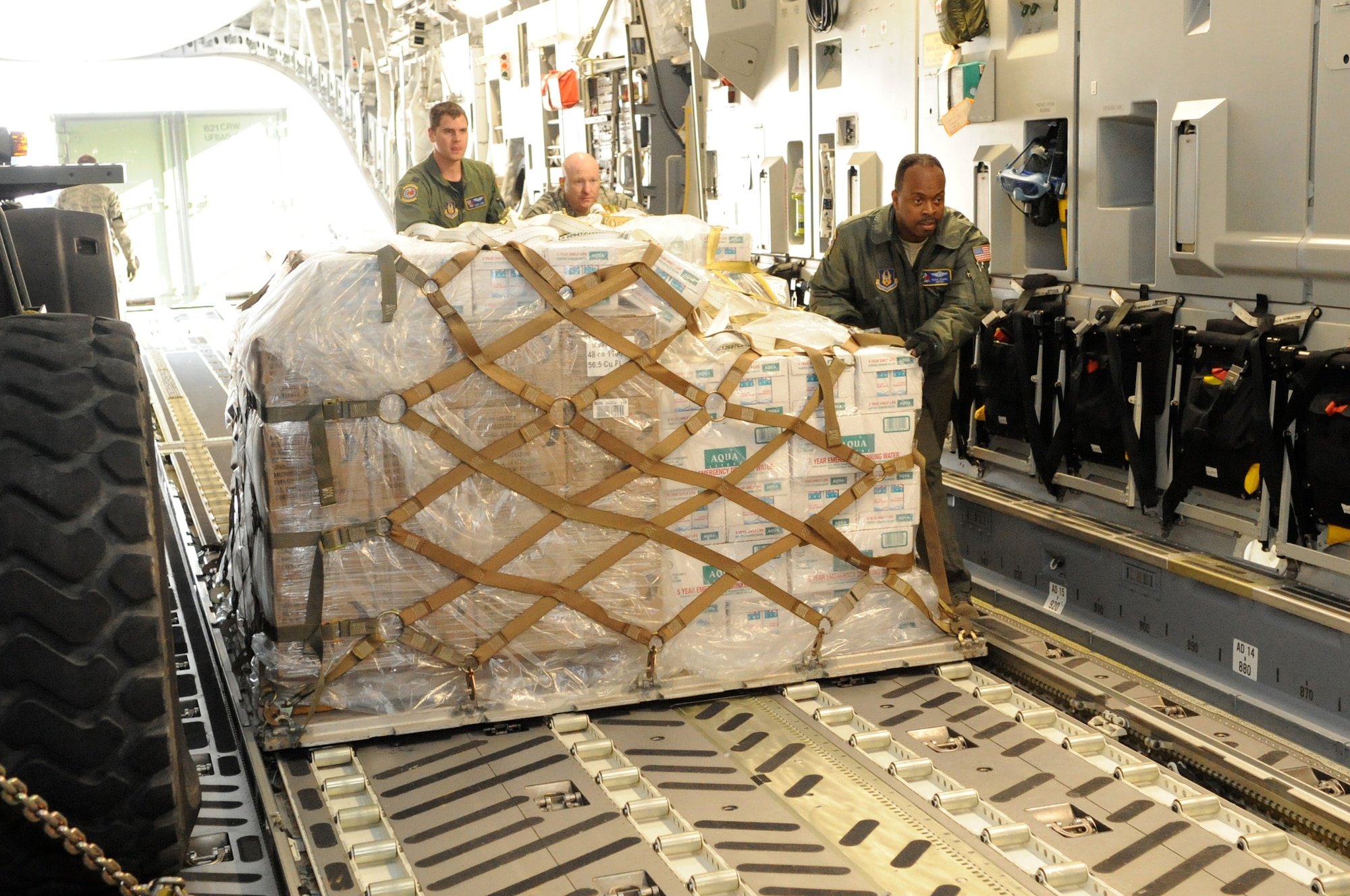 Airmen take the first step in providing relief supplies to Haiti Jan. 14, 2010, at Joint Base McGuire-Dix-Lakehurst. Together, they loaded bottles of water and other relief supplies on a C-17 Globemaster III in support of Haiti humanitarian relief operations. (U.S. Air Force photo/Charles Russell)