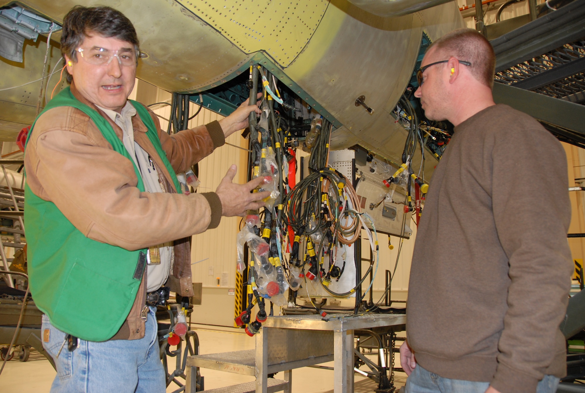 Keith Gilstrap, chief of the F-15 rewire flight, shows some of the wires in a critical area of the F-15 as aircraft electrician Robert Lamb looks on. U.S. Air Force Photo.
