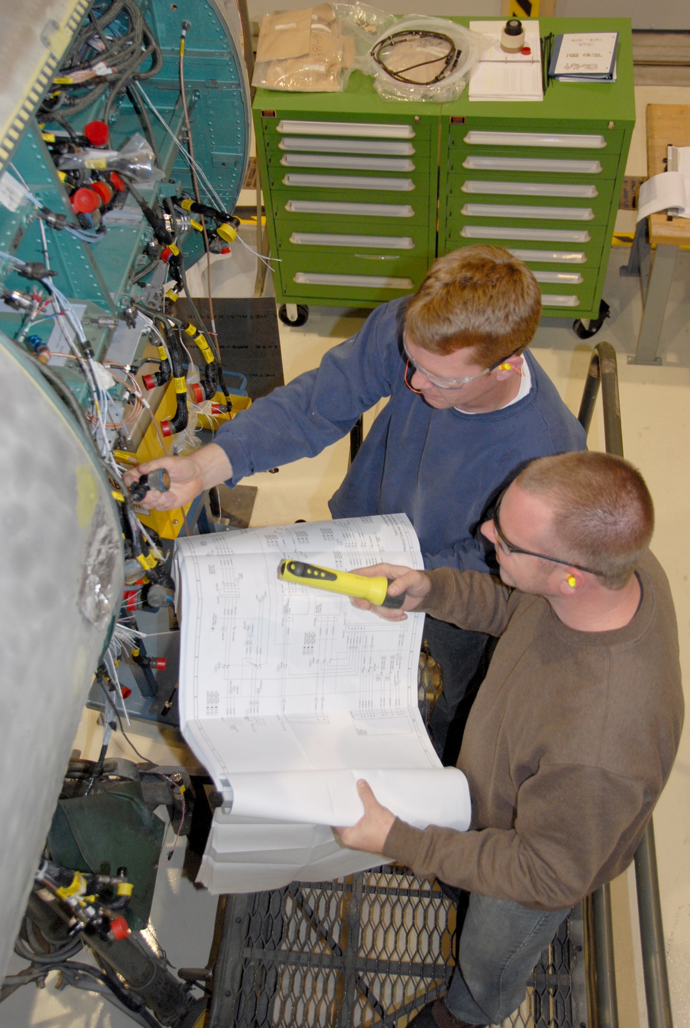 Aircraft mechanic Eric Bickett, left, and aircraft electrician Robert
Lamb use a diagram as they work on the F-15 rewire project. U.S. Air Force Photo.
