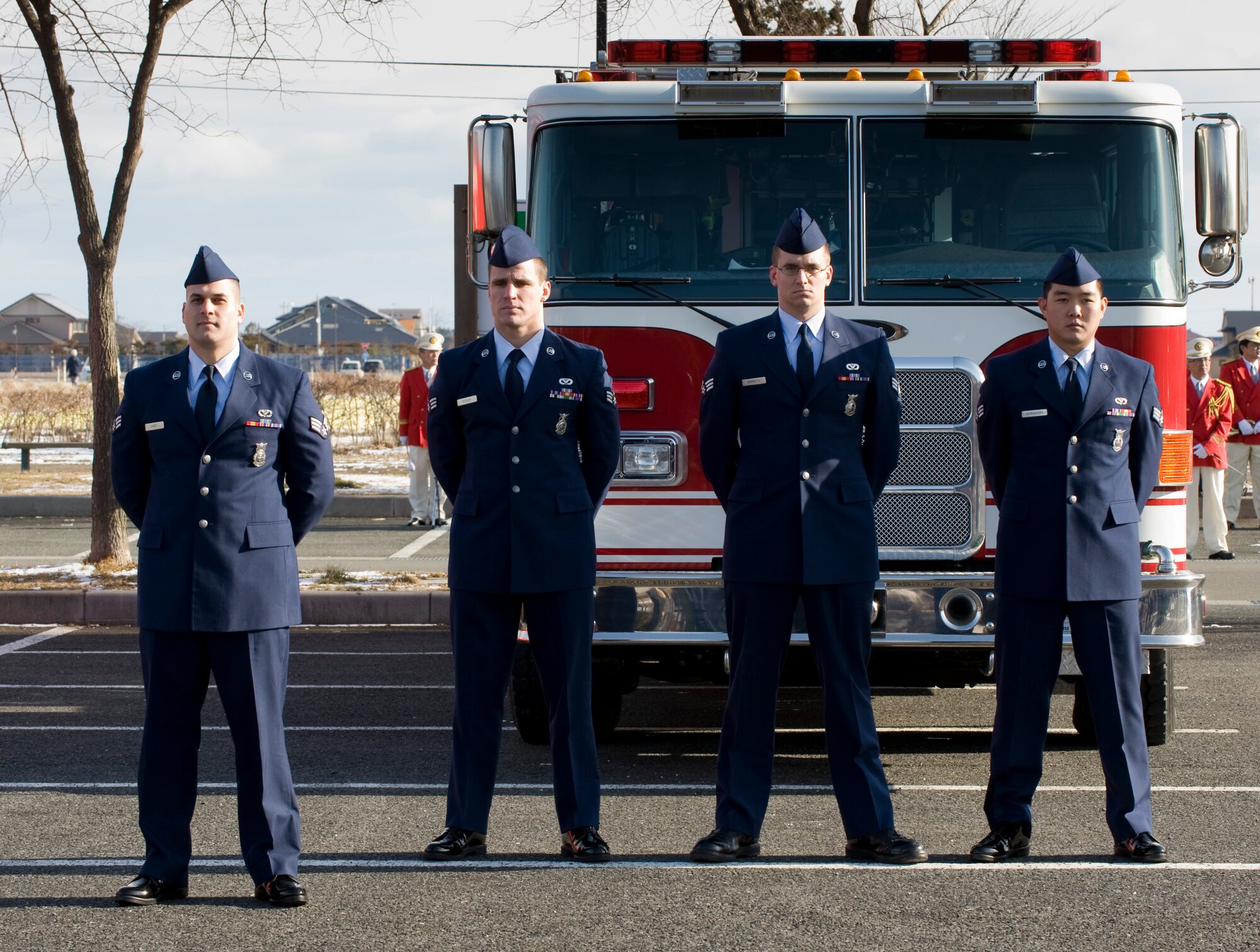 MISAWA CITY, Japan -- Senior Airmen Christopher Carey, Matthew Duggan, Eric Barrett and Jason Kawaguchi, 35th Civil Engineer Squadron firefighters, stand in formation in front of their fire truck during the fire truck review portion of the Misawa City Fire Department New Year's Ceremony at the Misawa Ice Arena Jan. 11. The Airmen represented the 35th Fighter Wing during the ceremony. (U.S. Air Force photo/Staff Sgt. Samuel Morse)