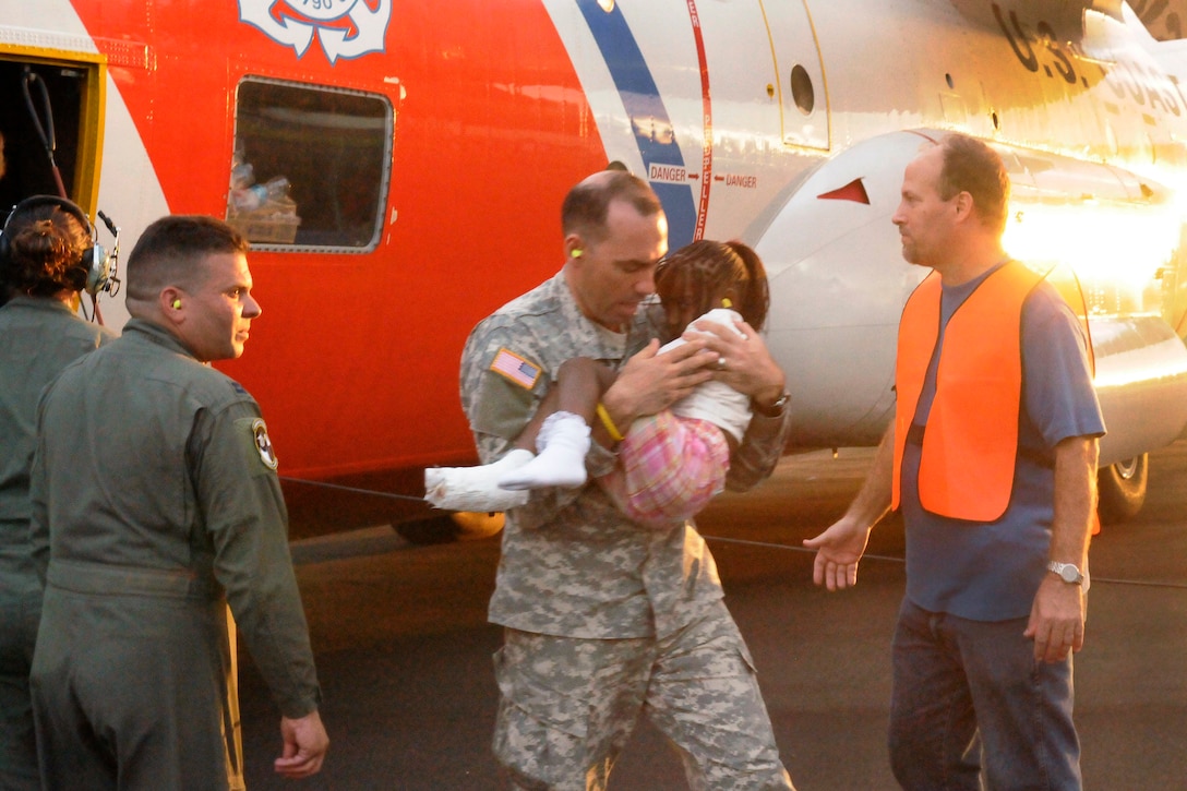 U.S. Army Lt. Col. Hector Paz carries an injured girl to receive medical treament in Santo Domingo, Dominican Republic, after being evacuated from Port-au-Prince, Haiti, by a Coast Guard HC-130 Hercules aircraft crew stationed in Clearwater, Fla., Jan. 14, 2010. Paz is assigned to the U.S. Military Assistance Advocacy Group at the U.S. Embassy in Santo Domingo.  