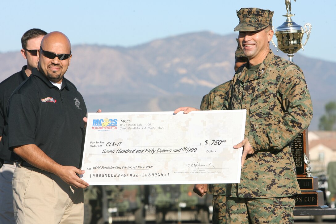 Eddie Bolanos, 46, from Oceanside, Calif., Marine Corps Community Services athletic coordinator (left), presents a first place check in Division III of the 2009 United Services Automobile Association Cup to Col. Bruce E. Nickle, commanding officer of Combat Logistics Regiment 17, 1st Marine Logistics Group (right), during a formation at Camp Pendleton, Calif., Jan. 14. This is the first time CLR-17 has received the award since the establishment of the USAA Cup in 1973.