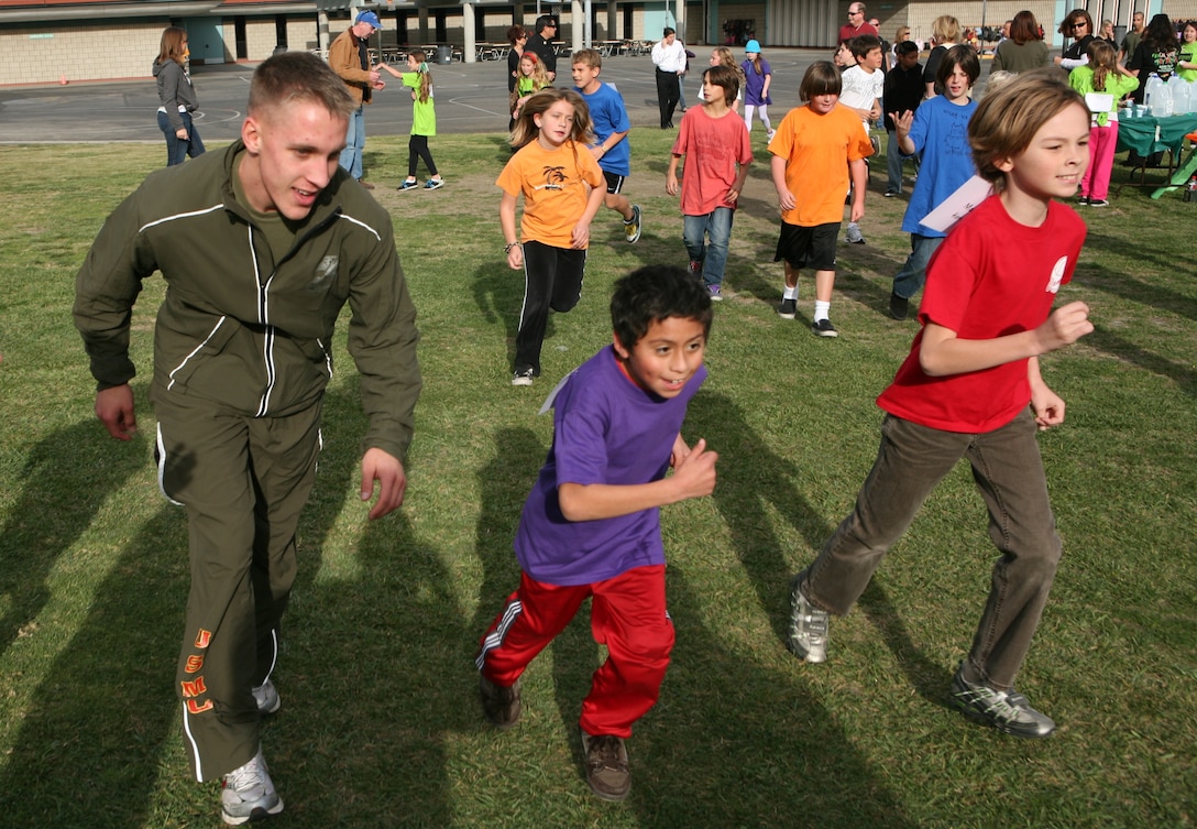 Lance Cpl. Chris A. DeCarmen, a chemical, biological, radiological and nuclear defense specialist with Headquarters Company, Combat Logistics Regiment 17, 1st Marine Logistics Group, 20, runs with Clarence Lobo Elementary kids in the school's annual Jog-a-Thon at San Clemente, Calif., Jan. 15.::r::::n::::r::::n::