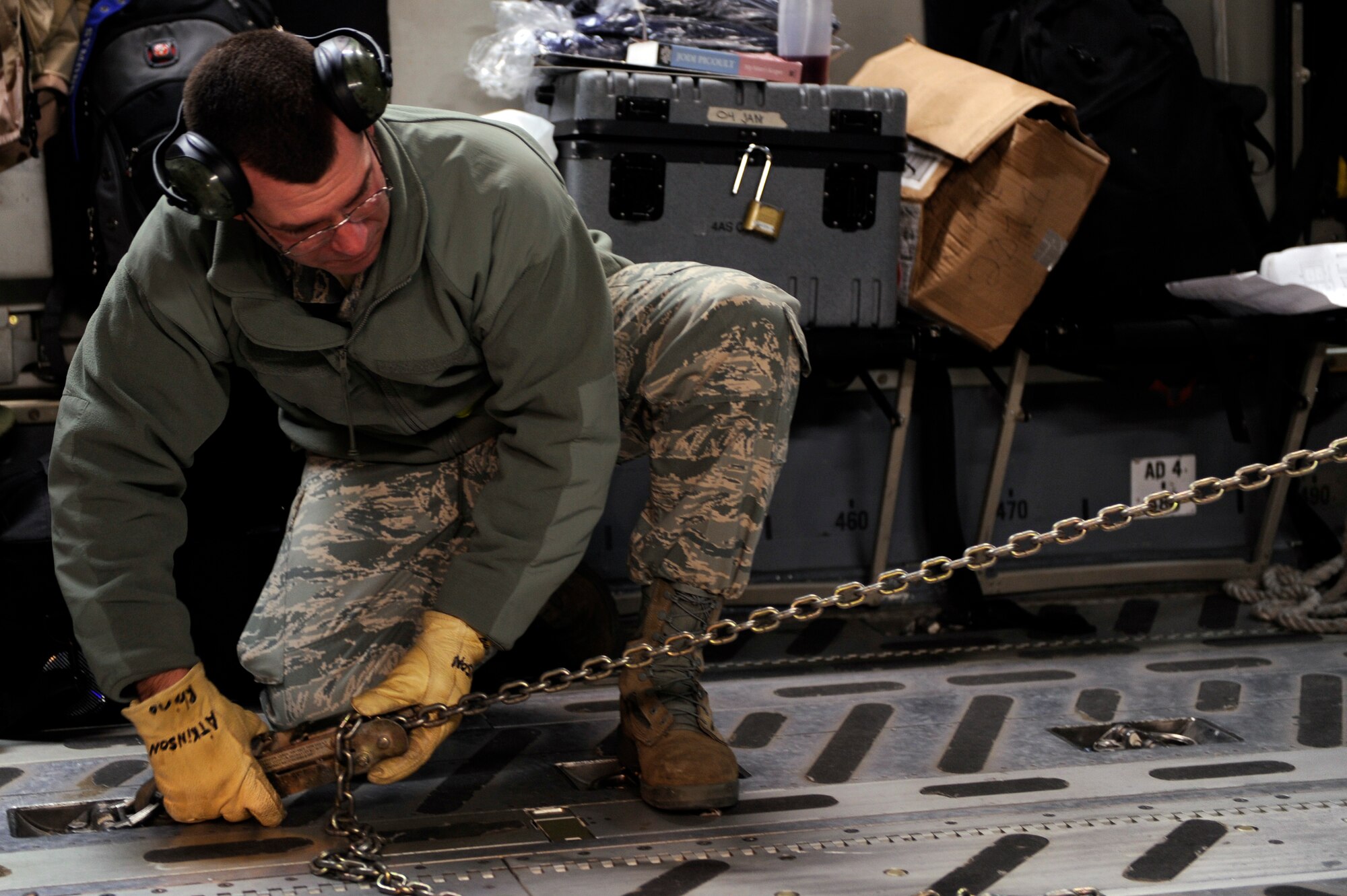 Master Sgt. Greg Kinney, 375th Logistics Readiness Squadron section chief small aircraft division, tightens a set of chains holding a military vehicle in place on board a C-17 aircraft while it gets loaded on the runway of Scott, Jan. 17, 2010. The C-17 along with it’s more than 40,000 pounds of medical supplies and aeromedical evacuation crews are headed to the Haiti to provide the medical relief in the wake of the recent earthquake. (U.S. Air Force photo/ Senior Airman Wesley Farnsworth)
