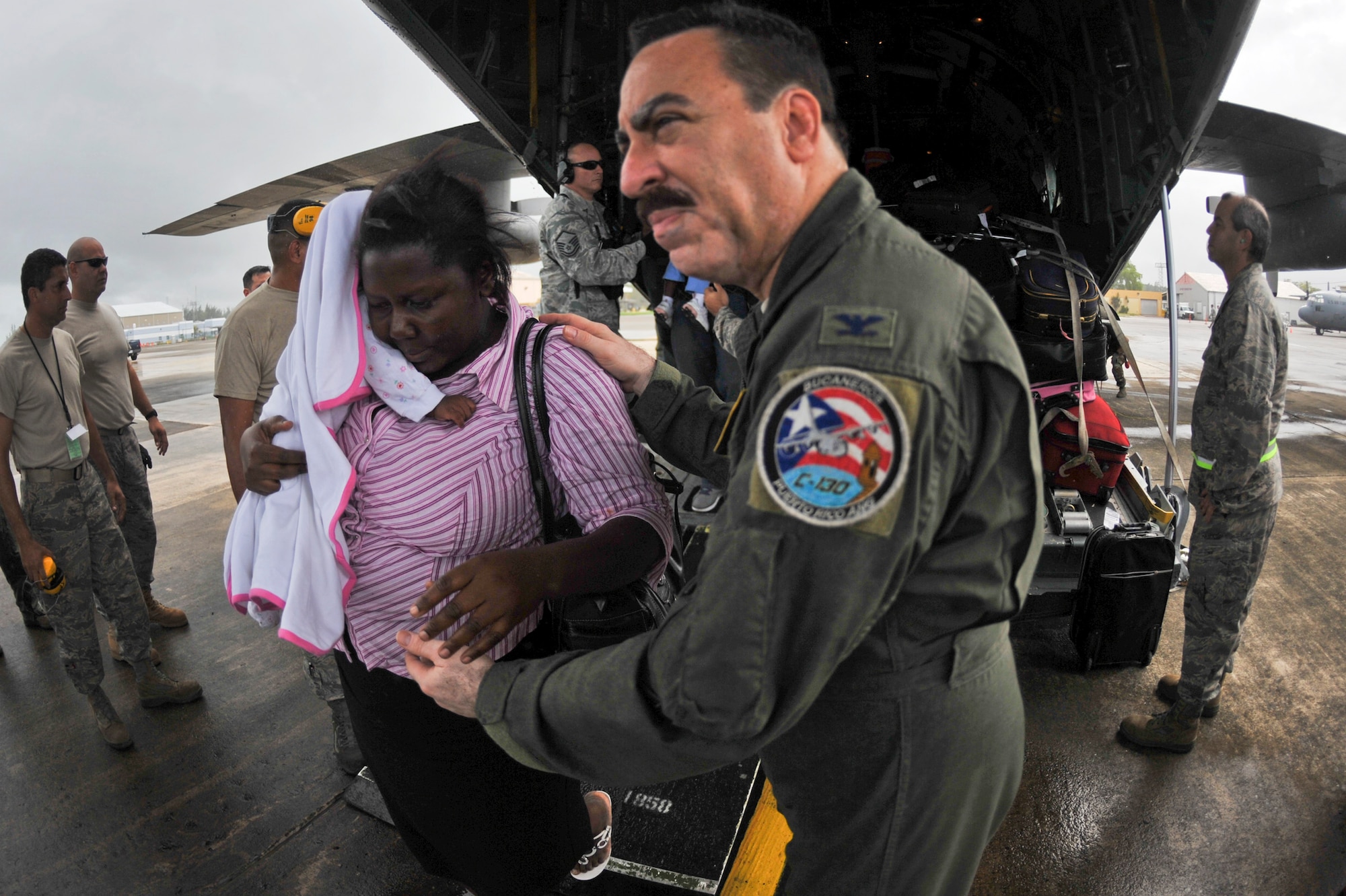 Col. Carlos Quinones assists a U.S. citizen living in Haiti off of a C-130E Hercules aircraft Jan. 17, that landed in San Juan, P.R. Colonel Quinones is the 156th Wing Commander. Airmen from the Puerto Rico Air National Guard's 156th Airlift Wing are working around the clock in support of the relief effort in Haiti in the aftermath of a devastating earthquake. (U.S. Air Force photo/Staff Sgt. Desiree N. Palacios)