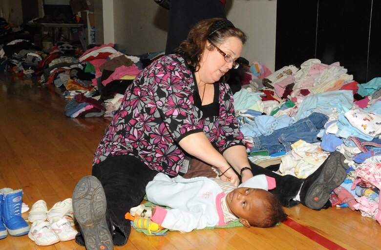 JOINT BASE MCGUIRE-DIX-LAKEHURST, N.J. – Patricia Sims, 87th Medical Group Family Advocacy consultant, dresses a baby in warmer clothing at the McGuire Fitness Center shelter for evacuees from Haiti. The center also is equipped with cribs, toys and baby formula for those with small children. (U.S. Air Force photo/Staff Sgt. Danielle Johnson)